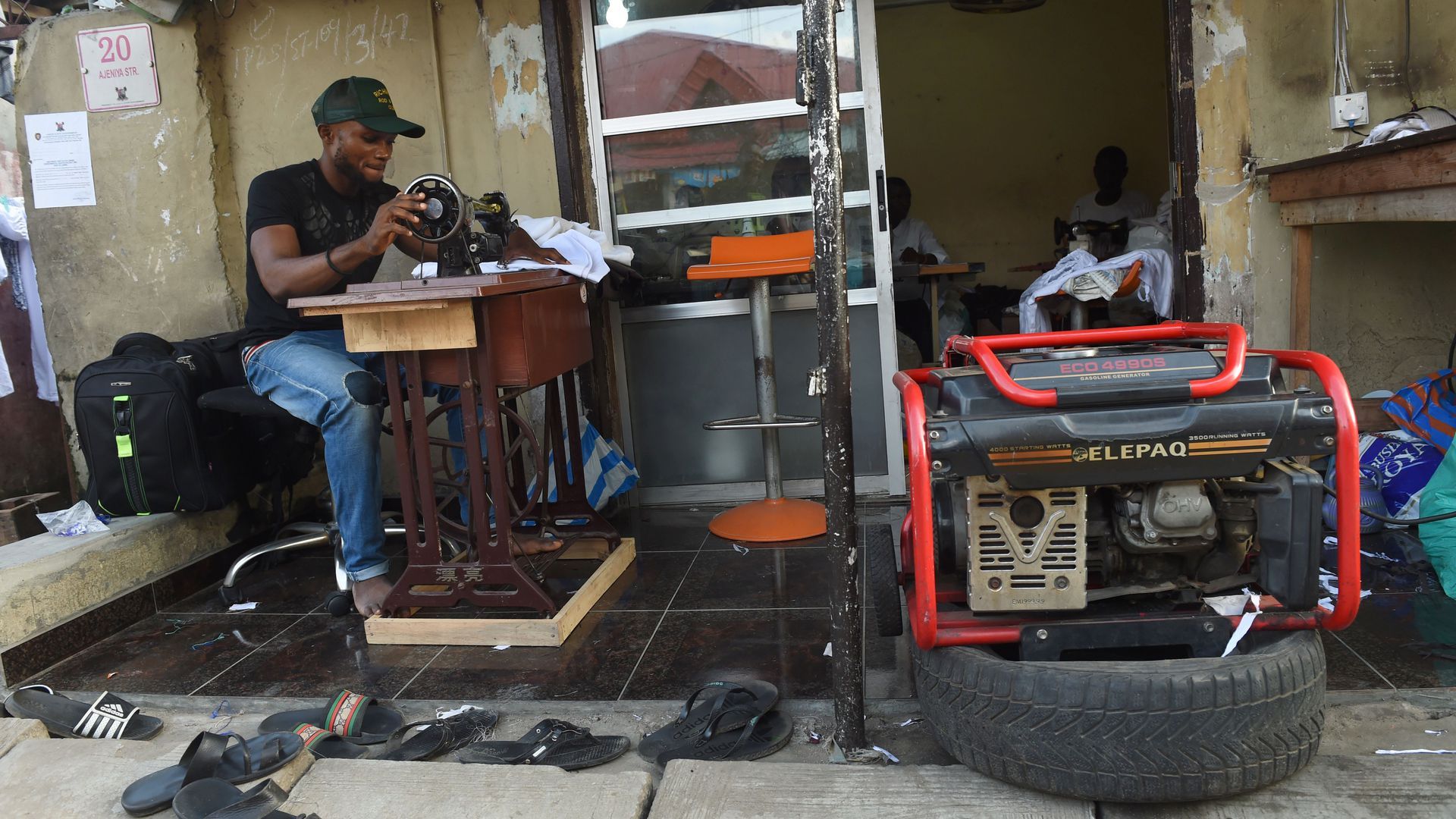 Photo of a tailor in Nigeria with a portable power generator attached to sewing machine