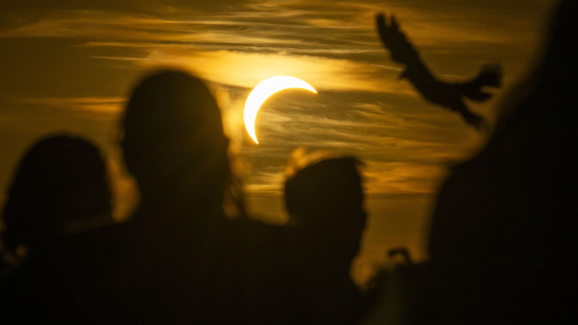A photo shows silhouettes of people's heads as they look up at a solar eclipse Wednesday, Aug. 12, 2026, in Bavaria, Munich.