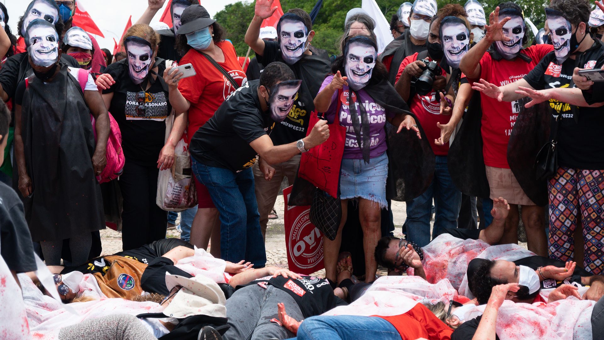 Protestors in "zombie" masks of Brazil President Jair Bolsonaro stand over their "victims." 