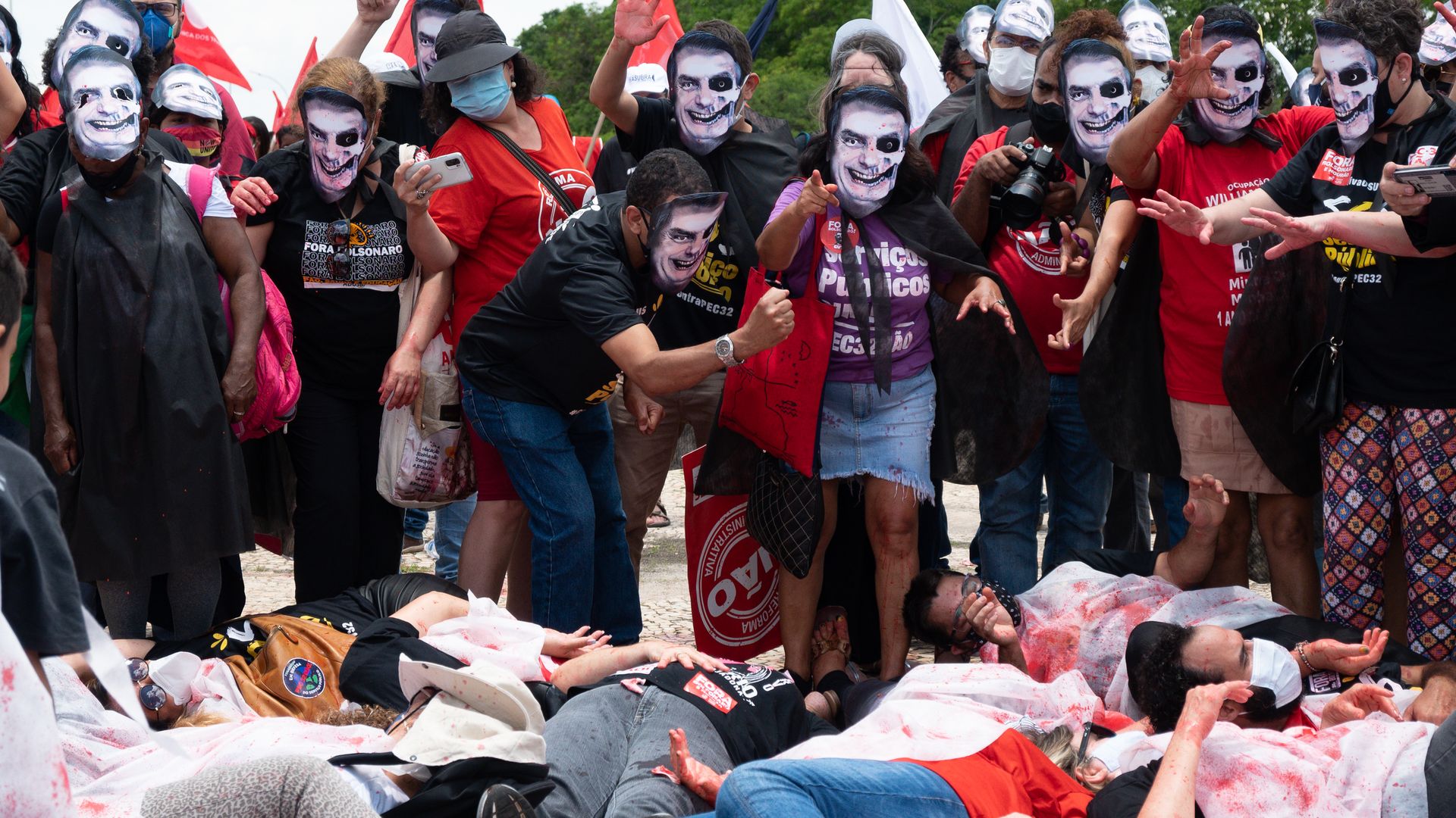Protestors in "zombie" masks of Brazil President Jair Bolsonaro stand over their "victims."