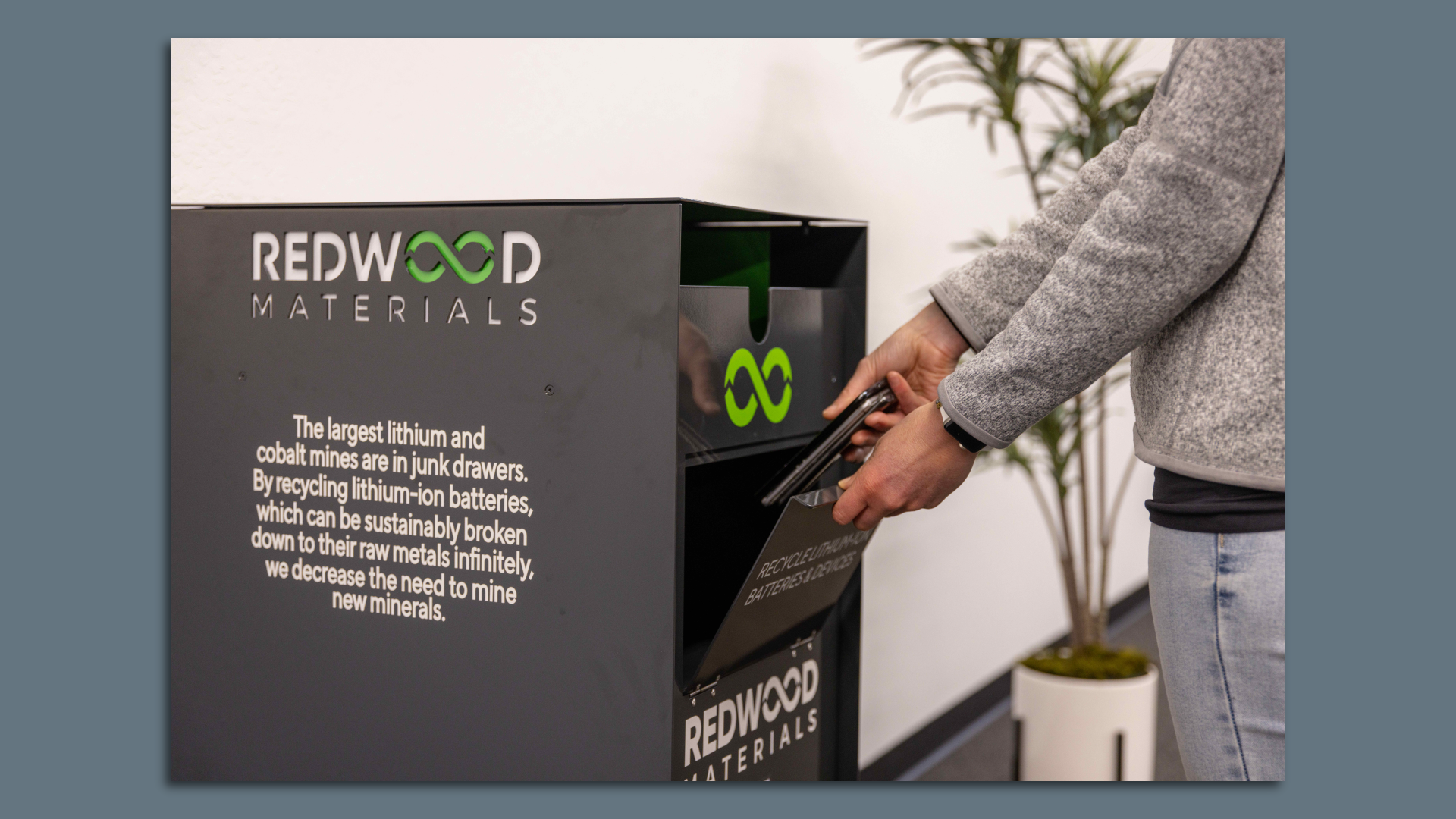 Image of a person dropping a cellphone into a battery recycling box operated by Redwood Materials