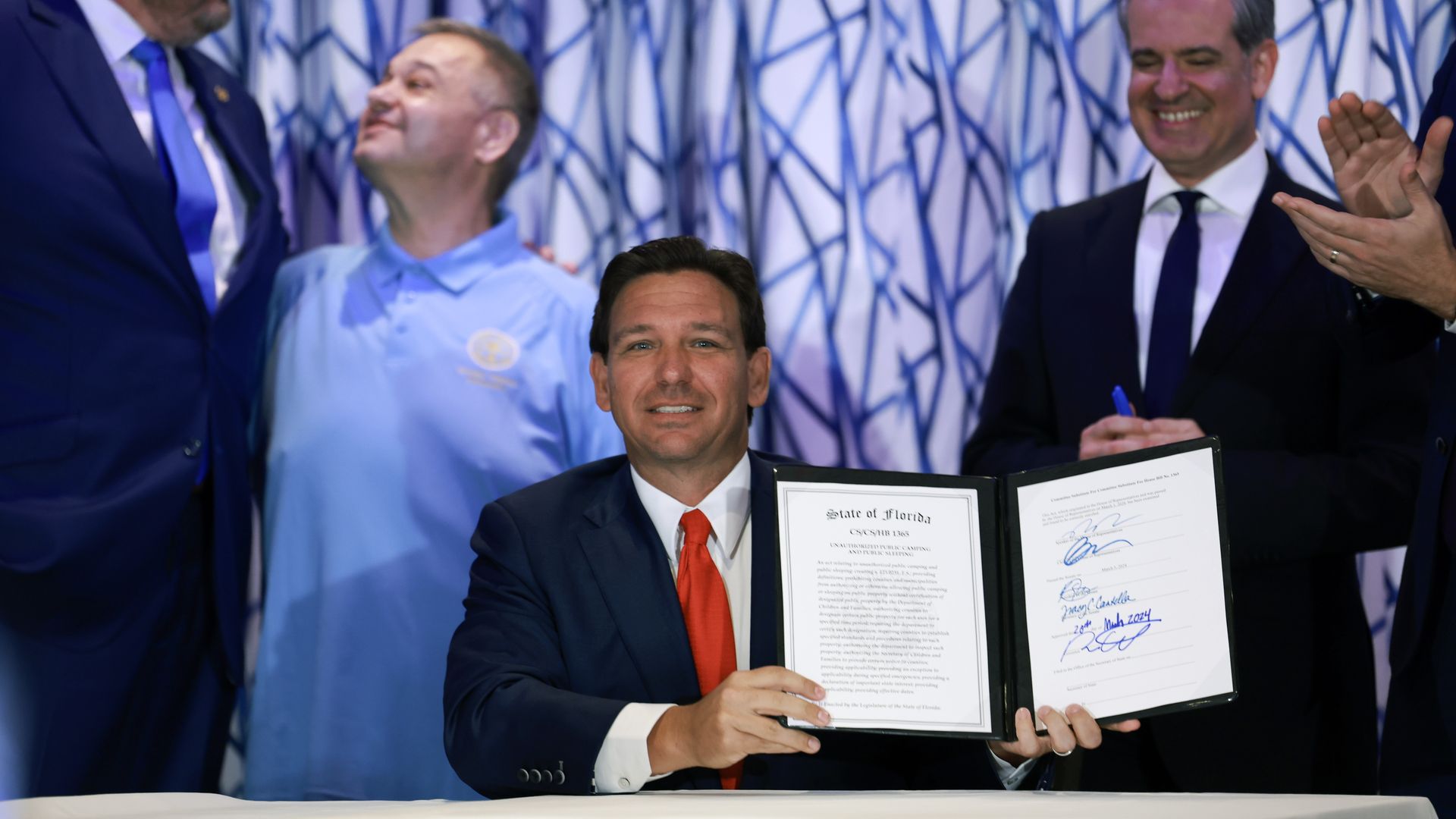 Gov. Ron DeSantis holding a signed law at a press conference in Miami Beach. 