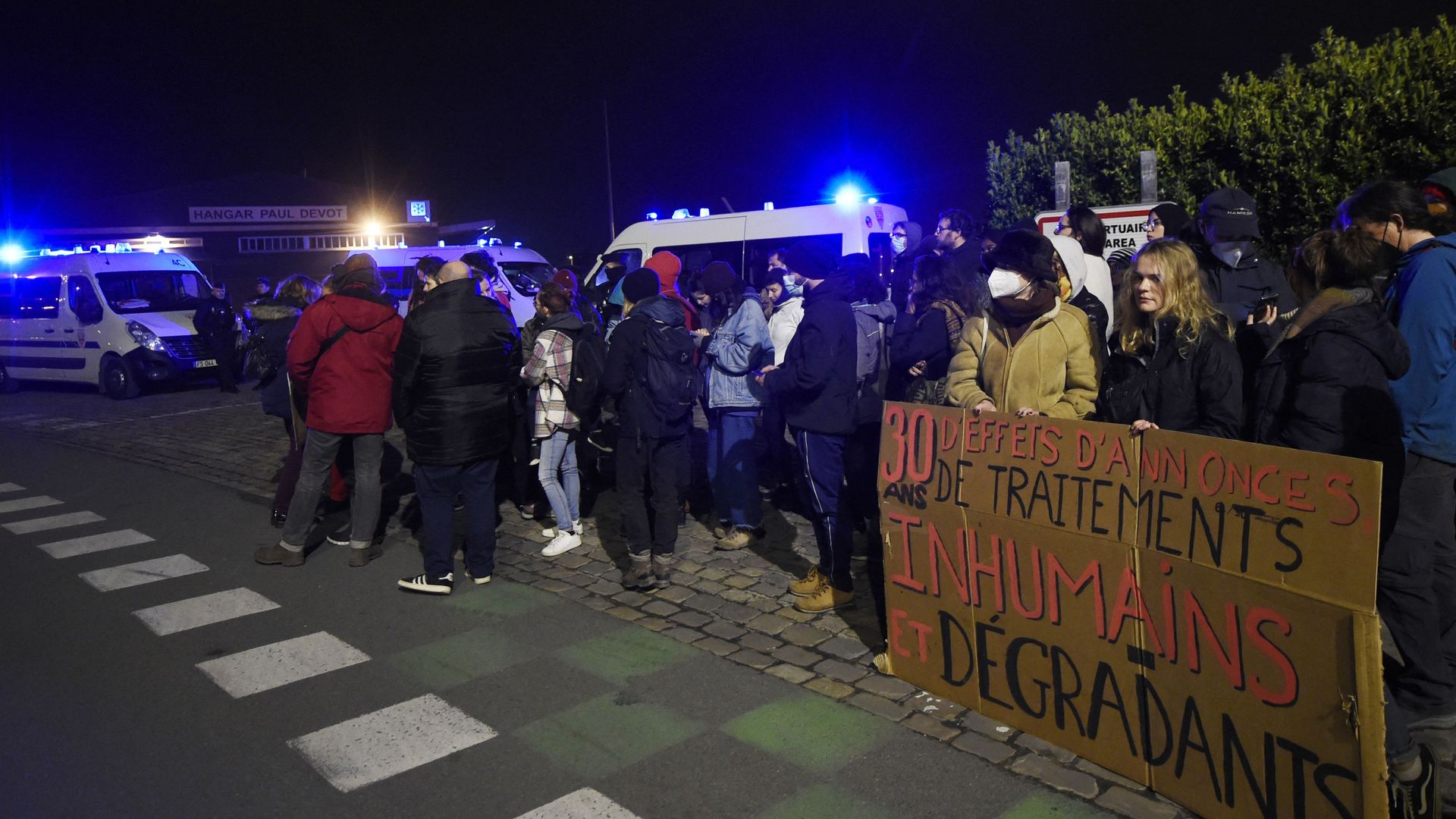 Migrant rights protesters with a sign reading "30 years of announcements, of inhuman and degrading treatment" on November 24 in Calais, France.