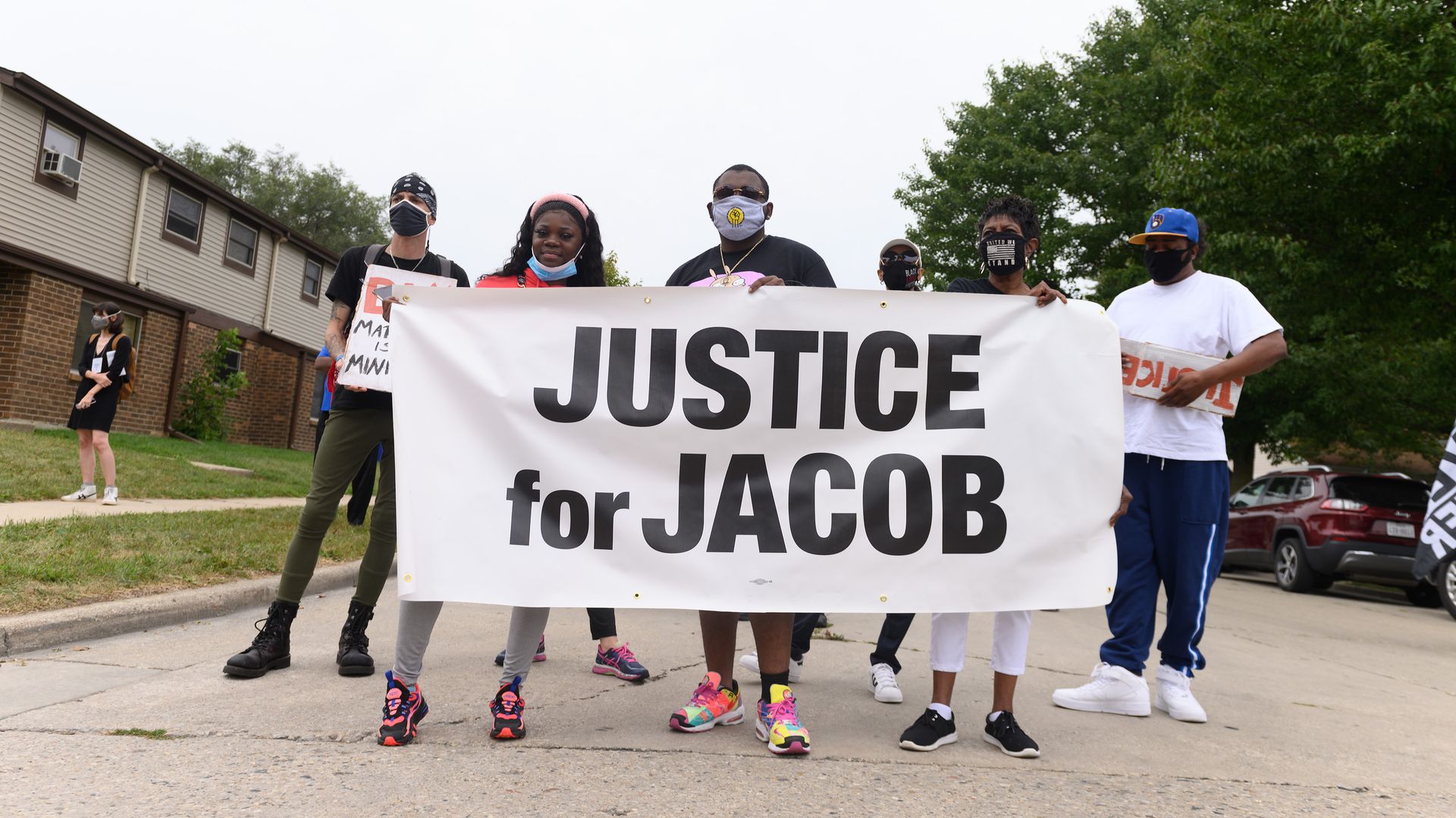 Protesters hold a banner during a community celebration and call for justice for Jacob Blake in Kenosha, Wis.