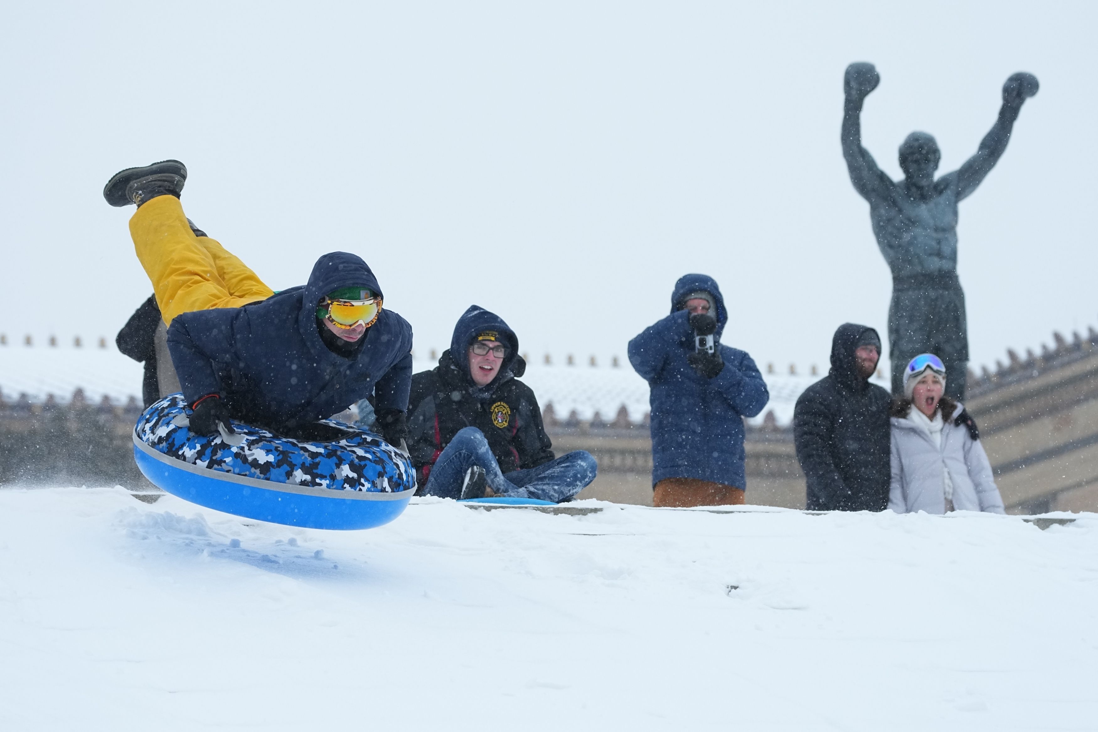 People sled on the steps of the Philadelphia Art Museum by the Rocky statue.