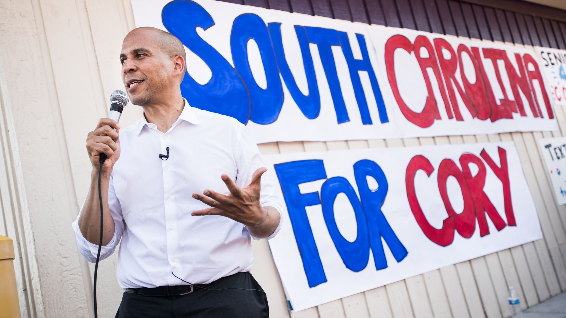 Cory Booker holds a microphone and stands in front of a sign that says "South Carolina for Cory."
