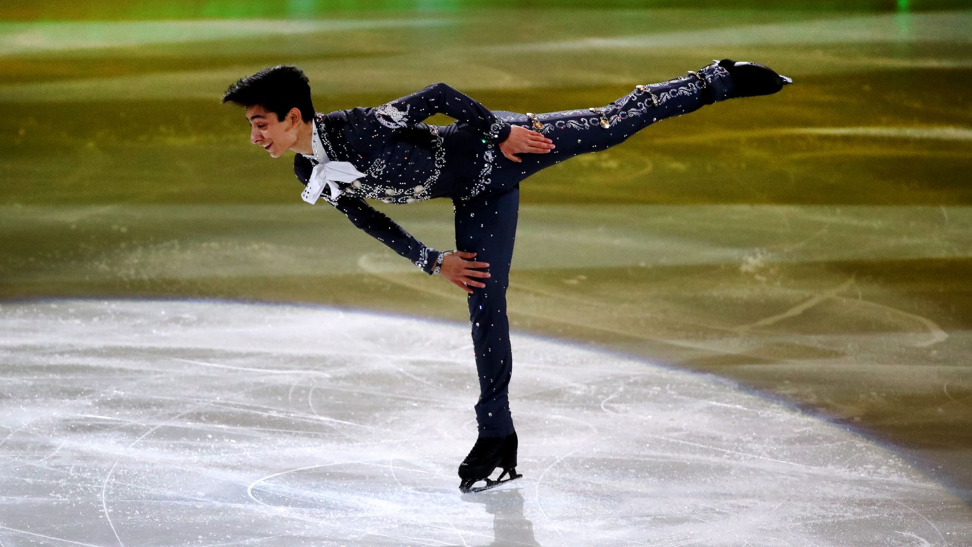 Olympic skater Donovan Carillo, wearing a mariachi outfit, skates on ice, his right leg in the air