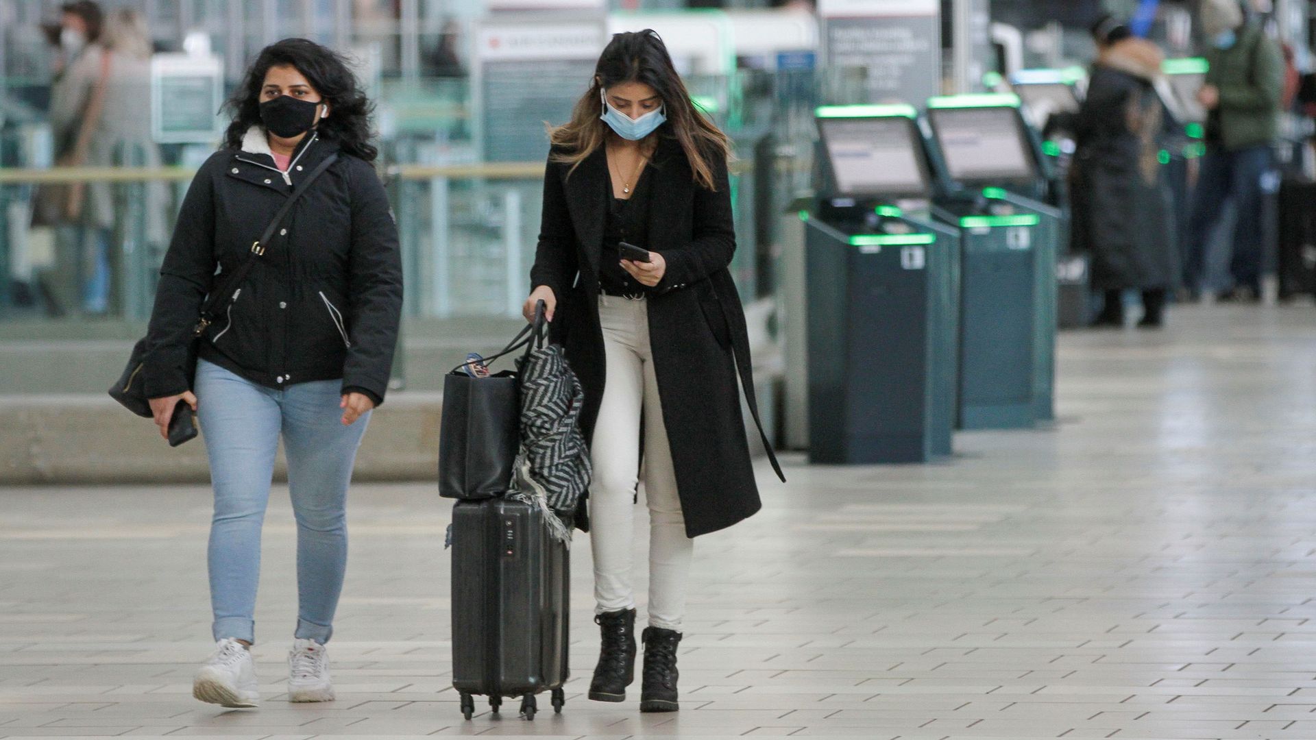 Picture of two women walking in the Vancouver International Airport while wearing masks