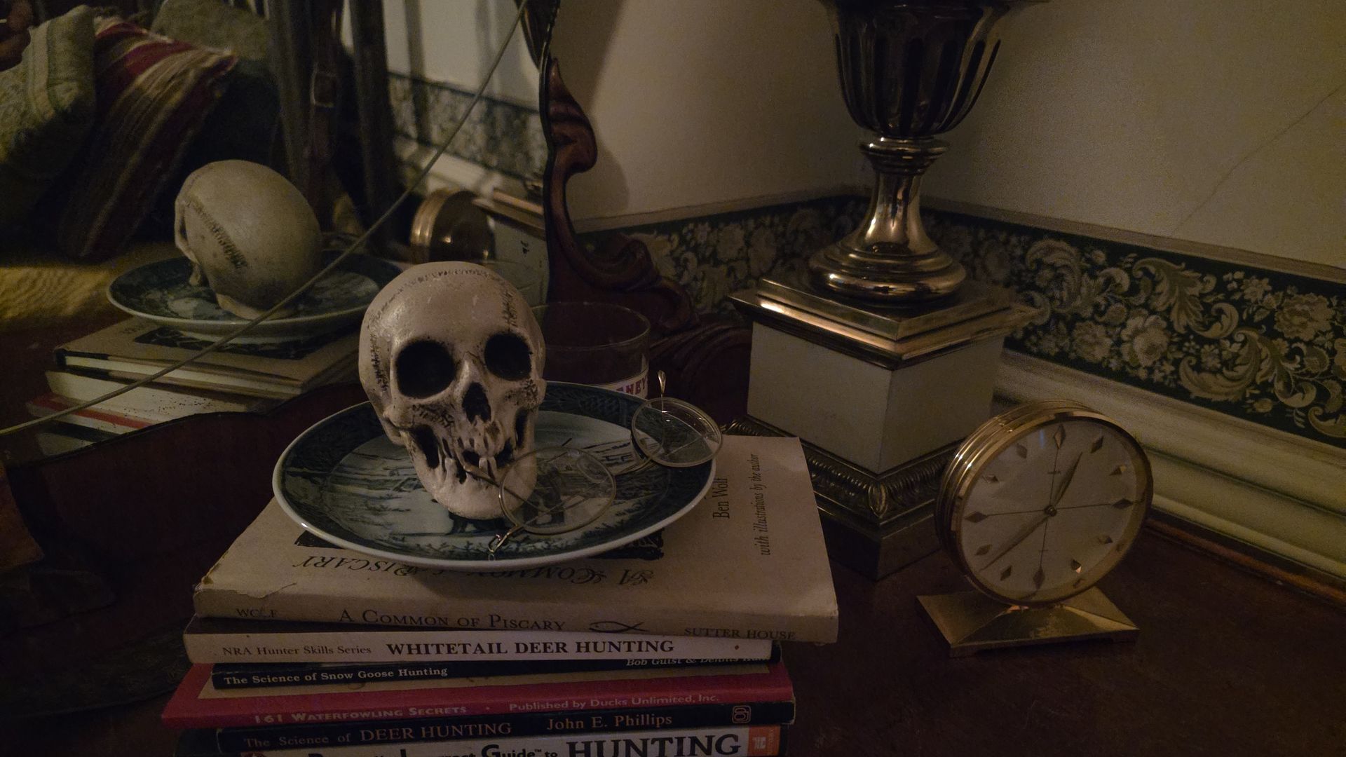 A small skull on a blue plate with glasses resting on it atop a stack of hunting books inside the Brinton Lodge.