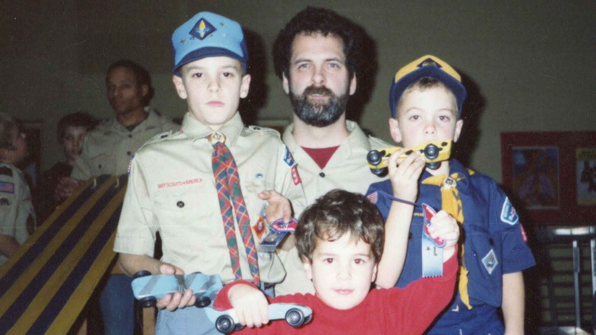 One white man and three white boys posing for a picture in Boy Scouts attire