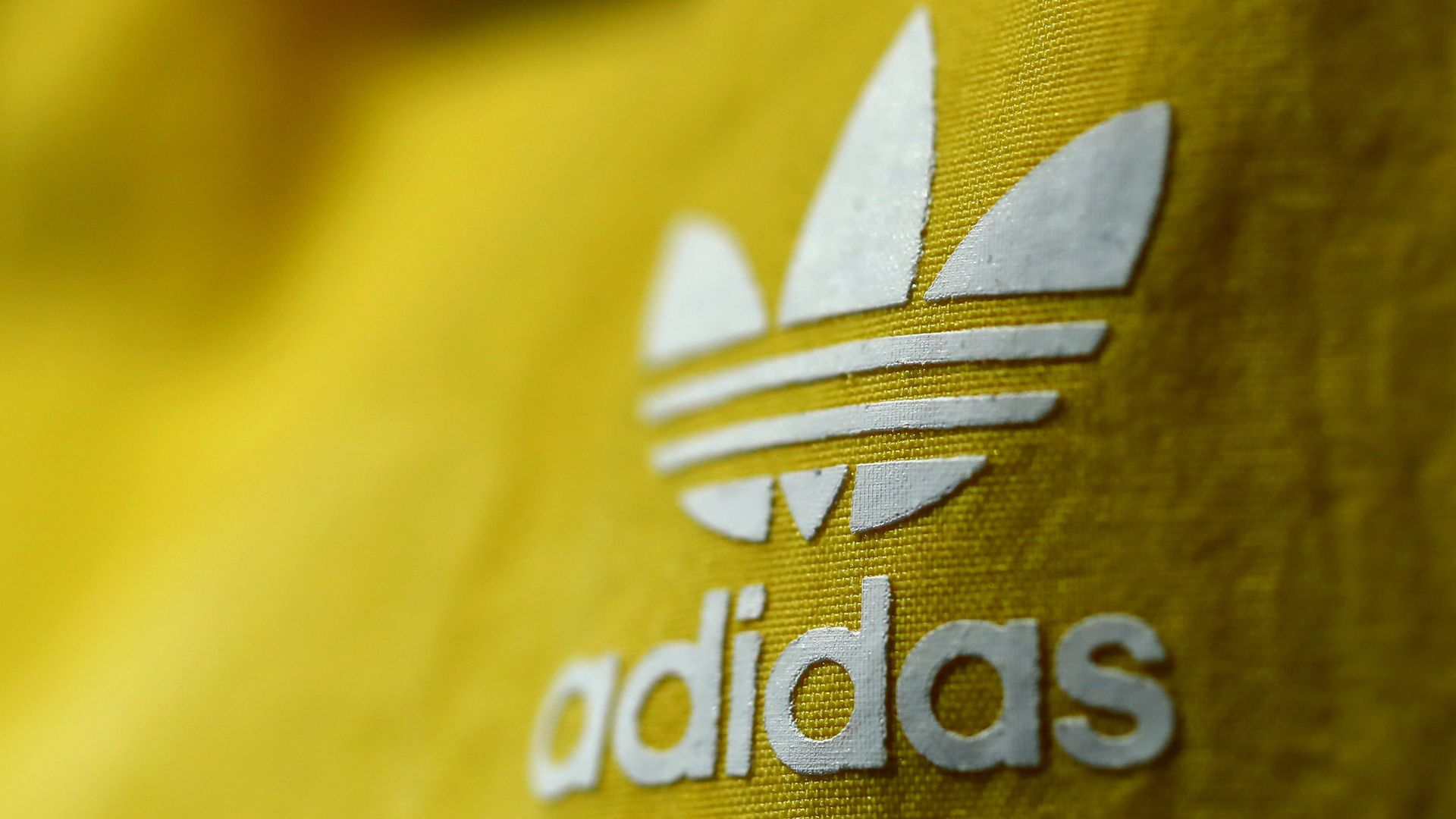 Adidas logo in white on yellow cloth.