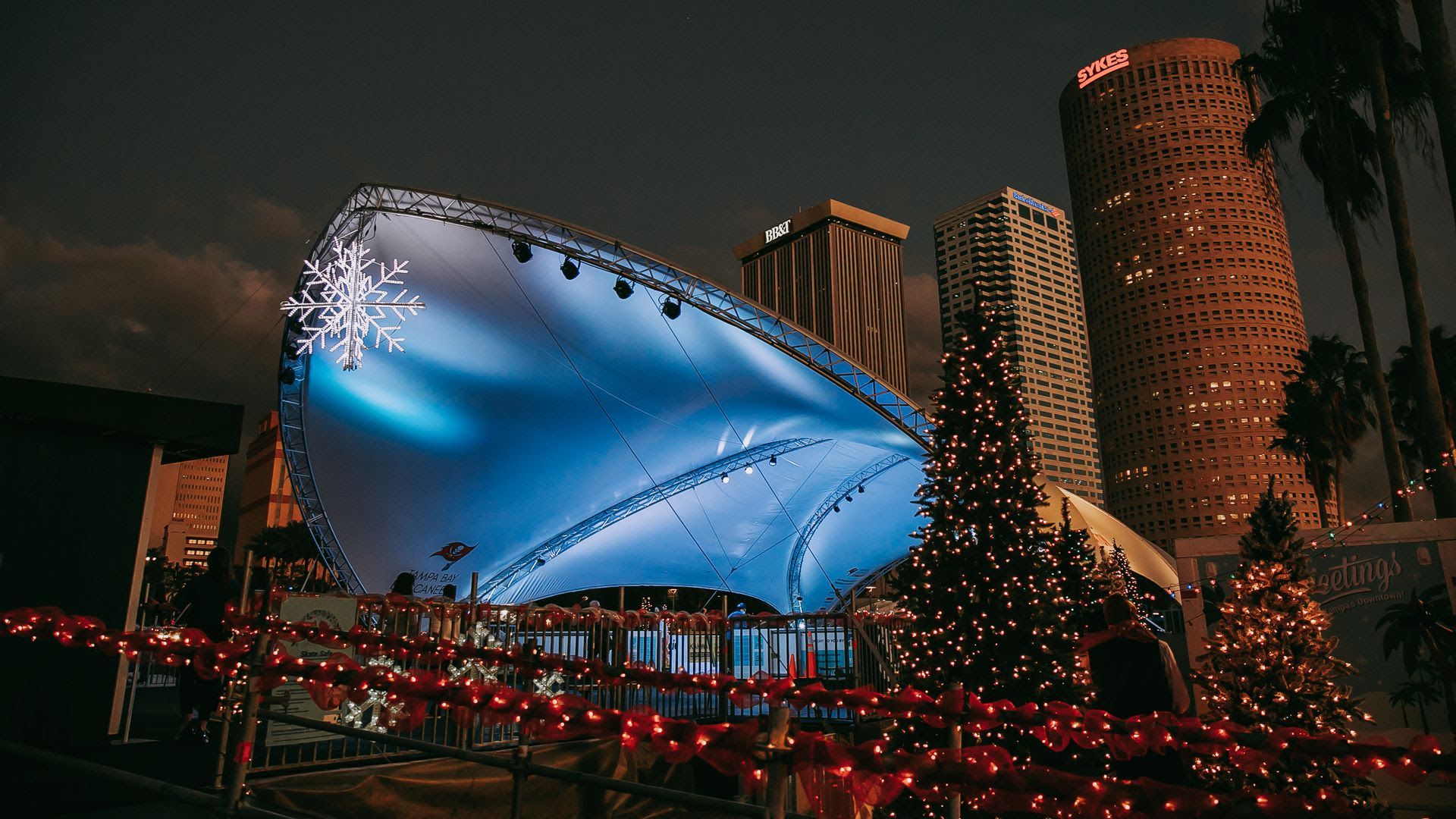 Downtown Tampa's Winter Village ice rink lit up with holiday trees and lights.