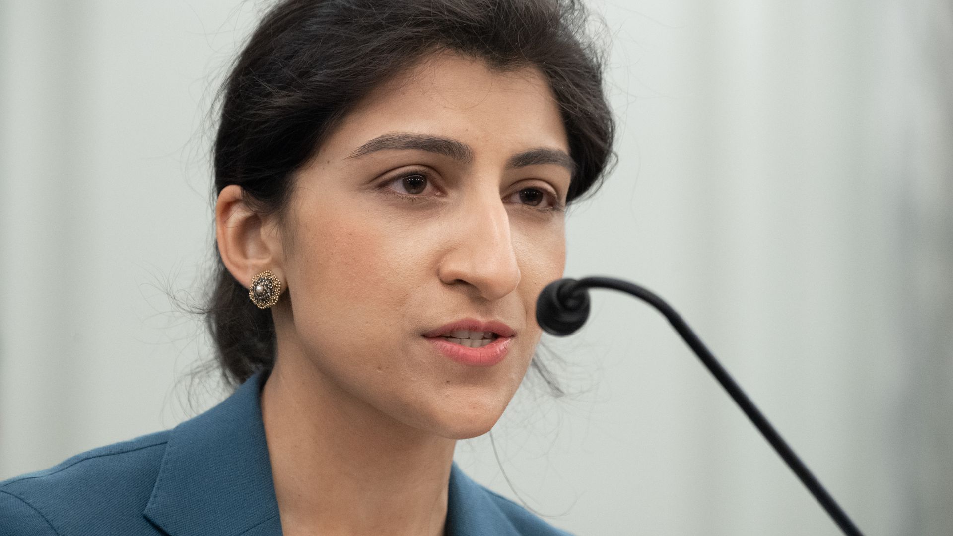 A photo of Lina Khan speaking at a microphone