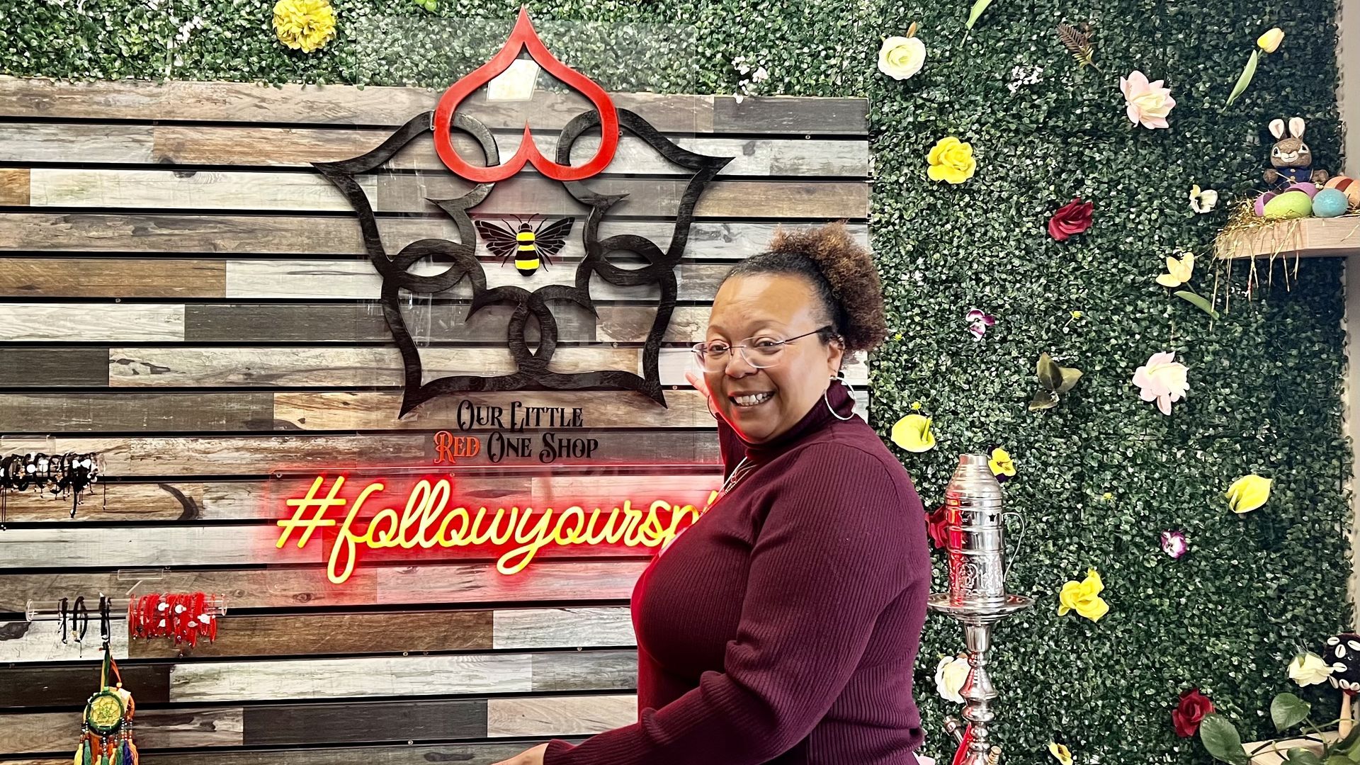 Photo of a woman in front of a store shop named "Our Little Red One Shop"