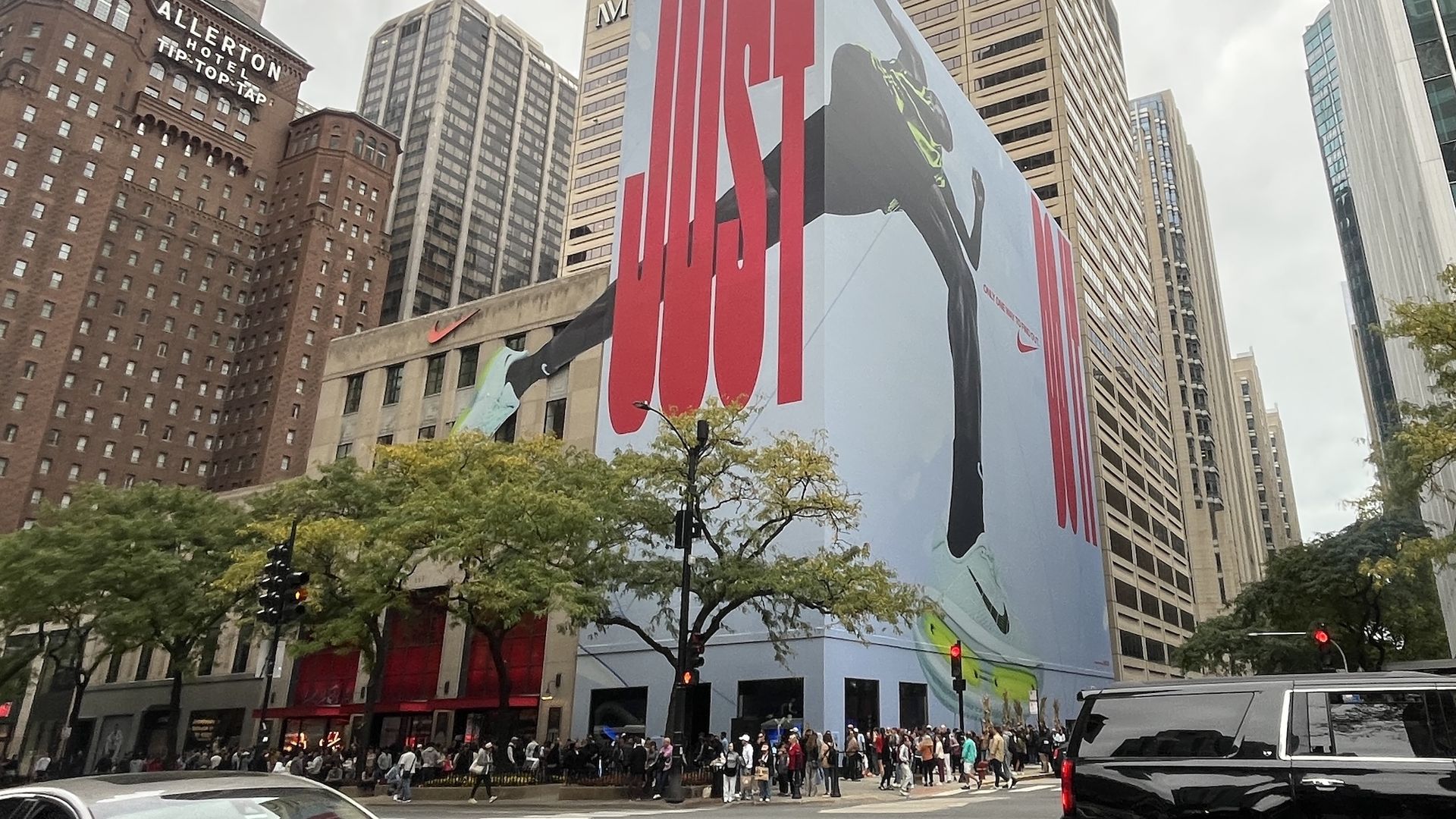 Large street mural advertisement on a city building showing a runner's legs wearing light blue Nike shoes with bright yellow soles, with the word "JUST" in big red letters.