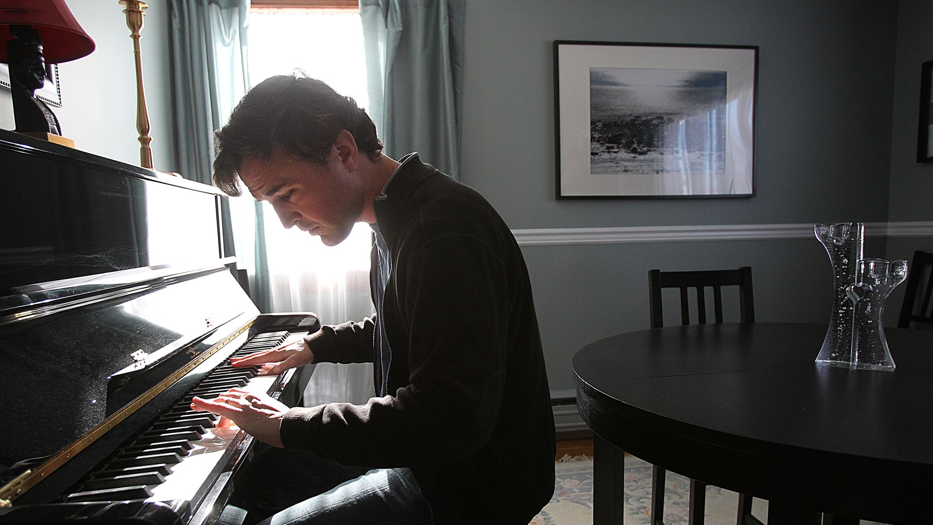 Matt Farley playing a piano in a dining room.
