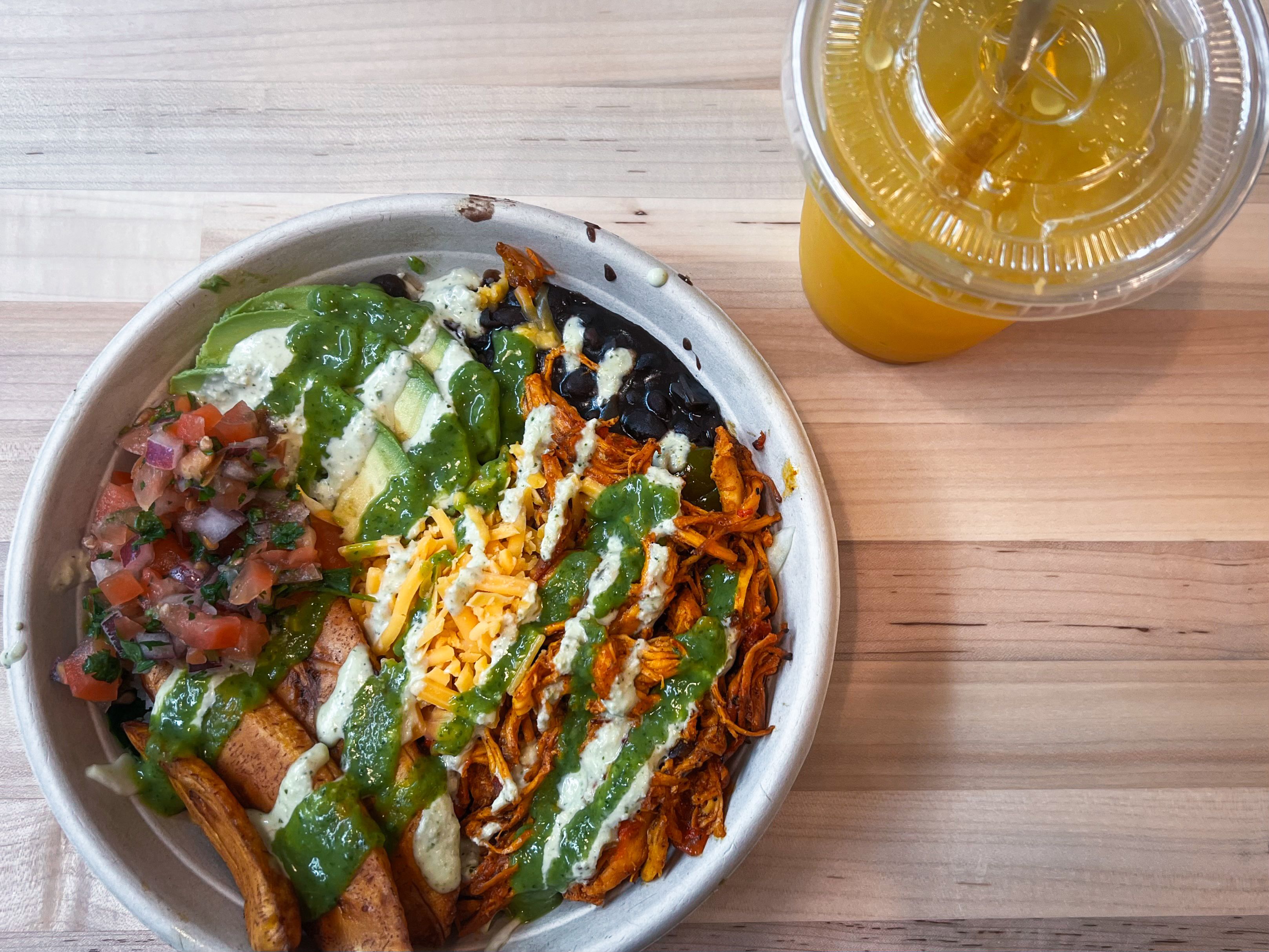 An arepa bowl with chicken and a drink.