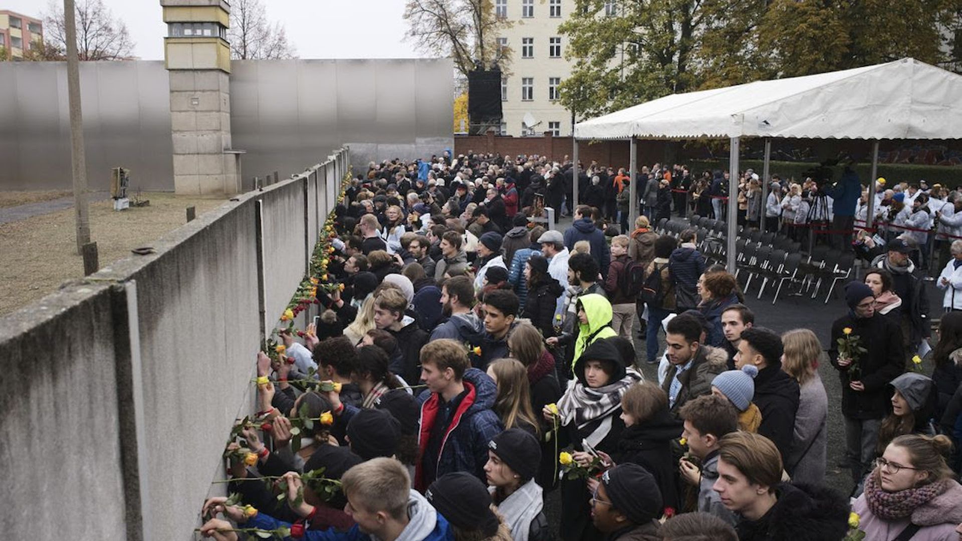 Young people stick flowers in remains of the Berlin Wall during a commemoration ceremony today