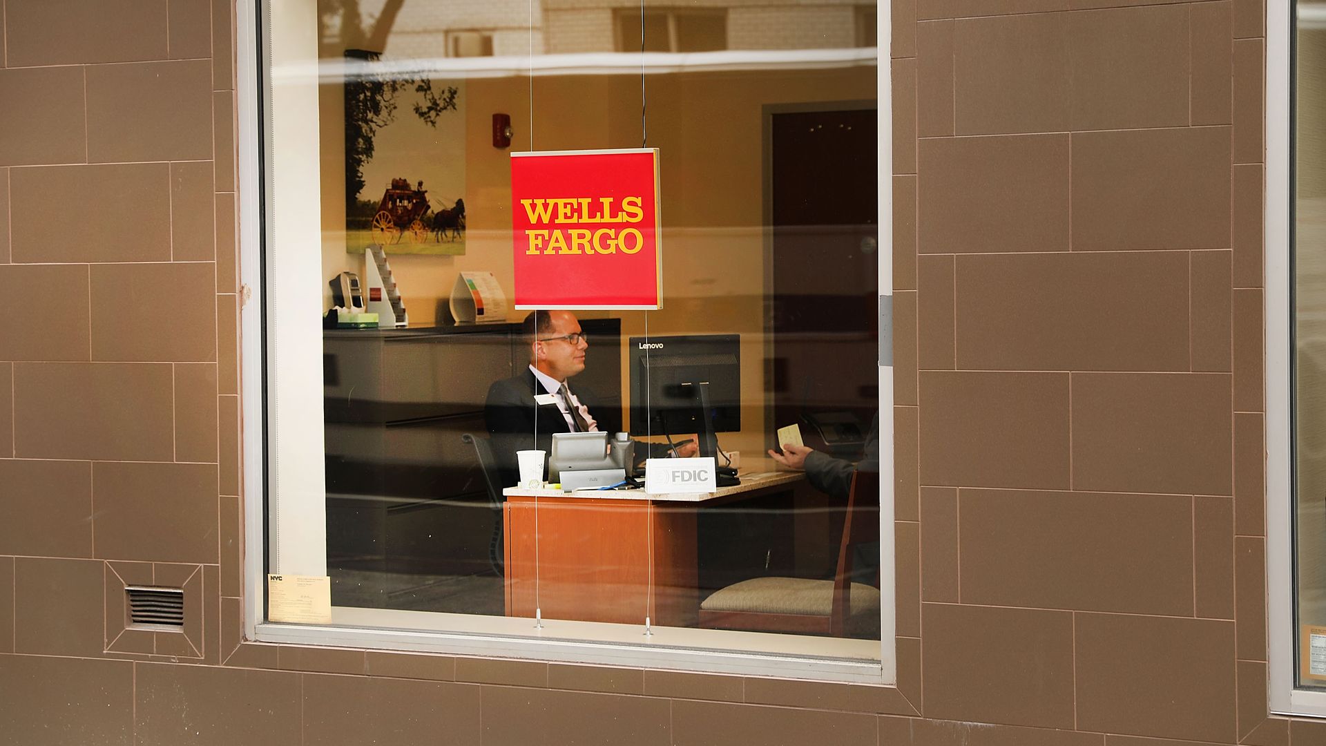 An employee sits inside of a Wells Fargo.