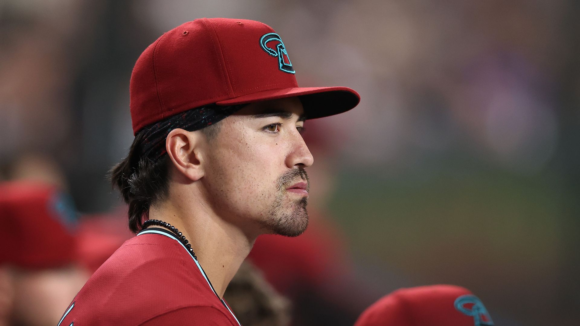 A baseball player watches the game from the dugout.