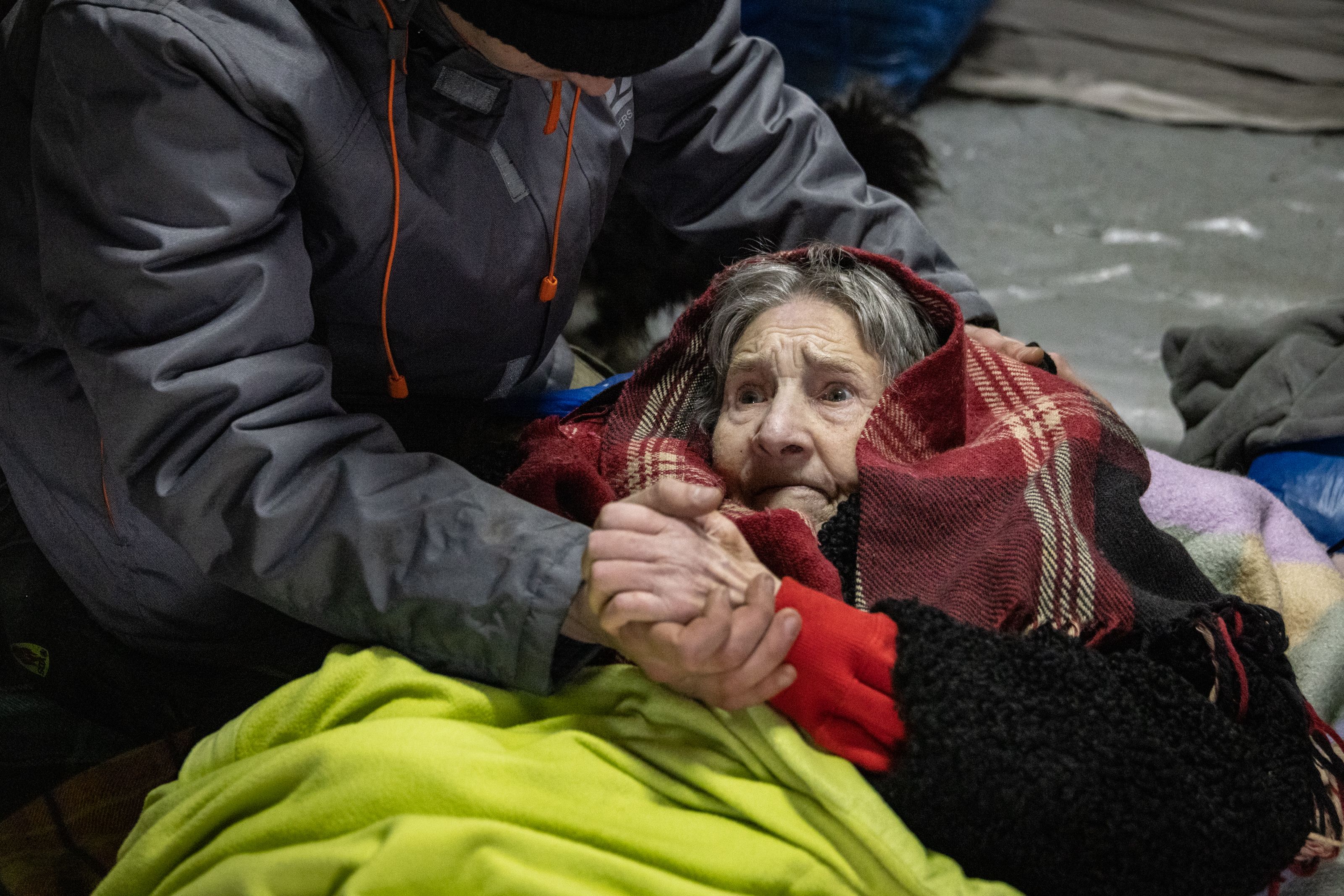 An elderly woman is assisted as Ukrainians cross an improvised path along a destroyed bridge to flee the city on March 8, 2022 on Irpin, Ukraine. 