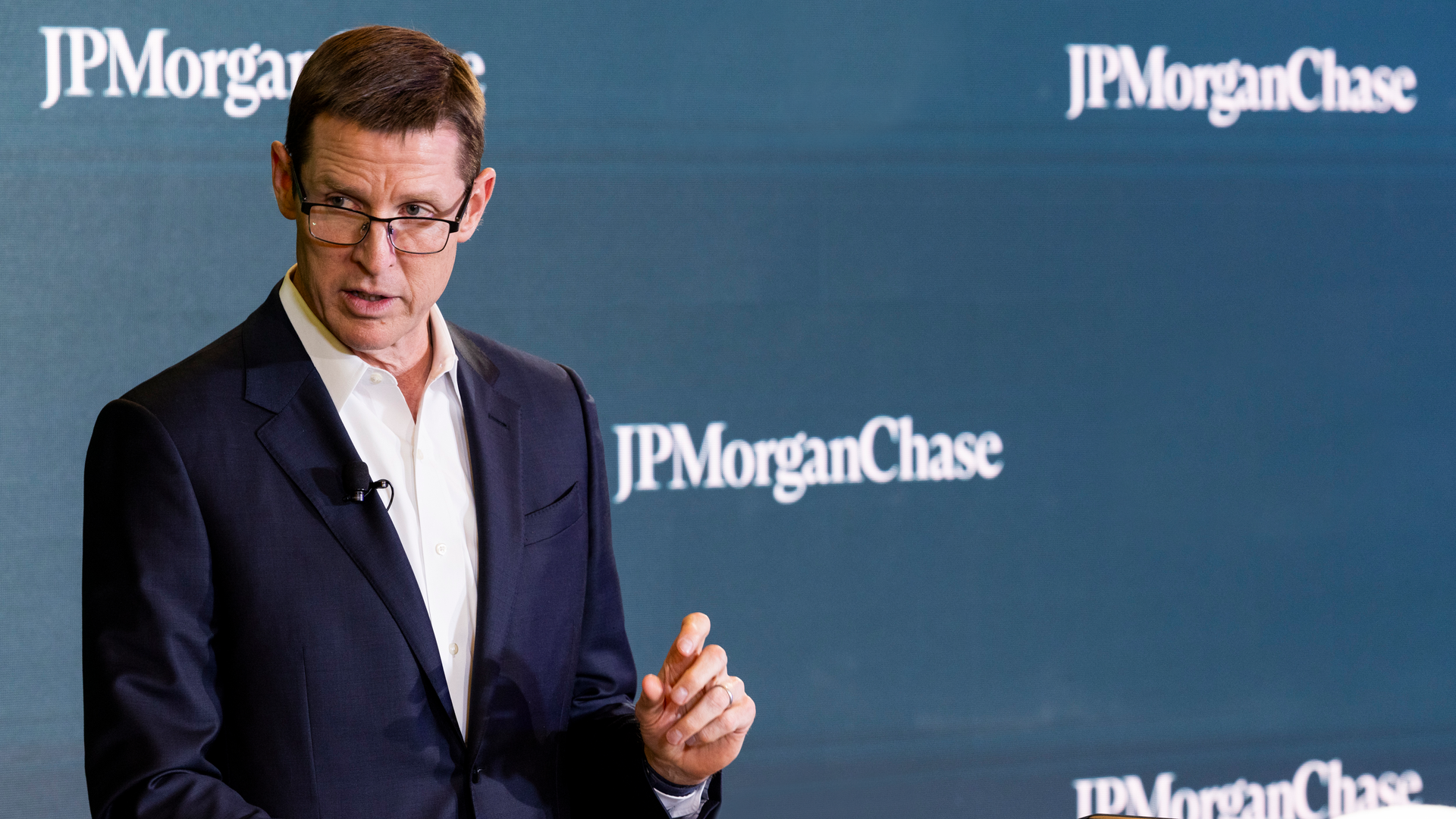 A man speaking in front of a JPMorganChase sign. 
