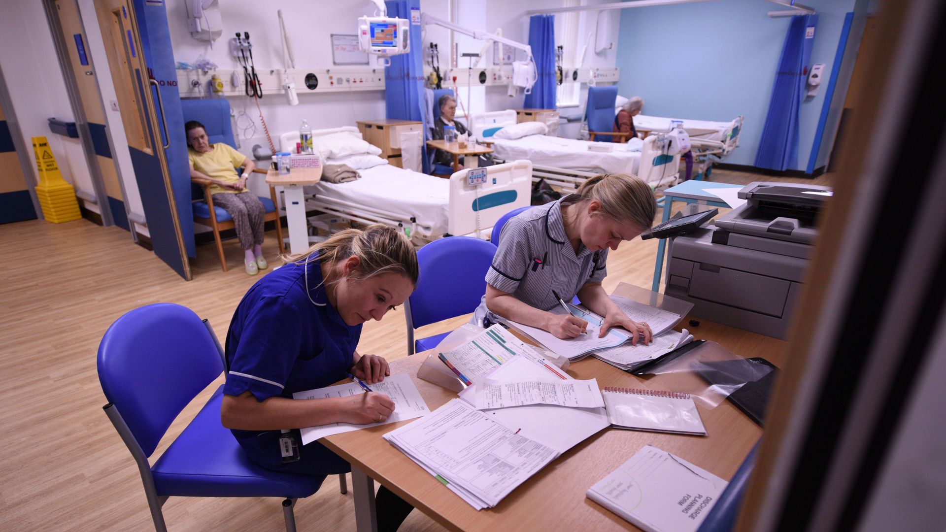 Nurses writing on papers near hospital beds