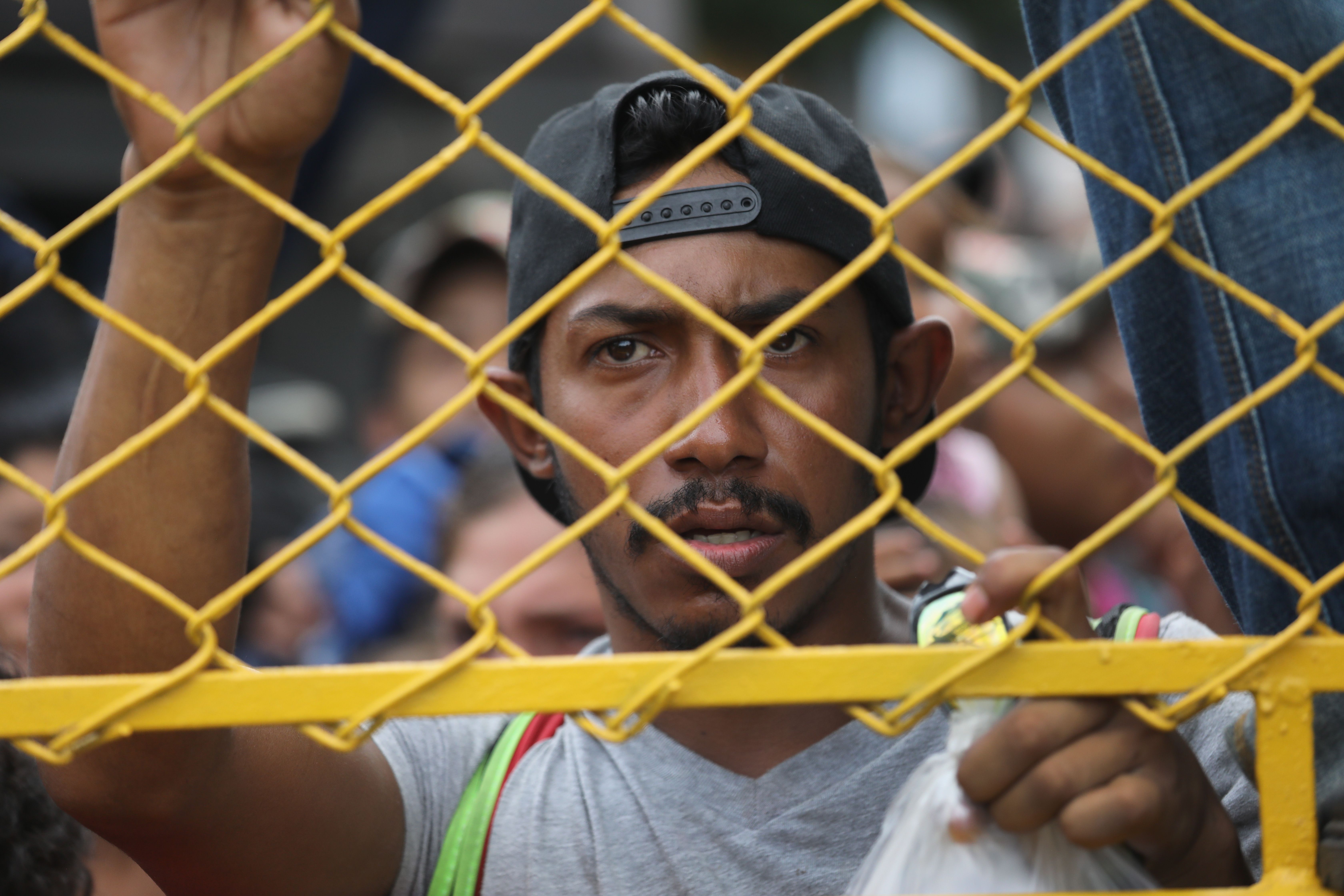A migrant at the gate separating Guatemala and Mexico
