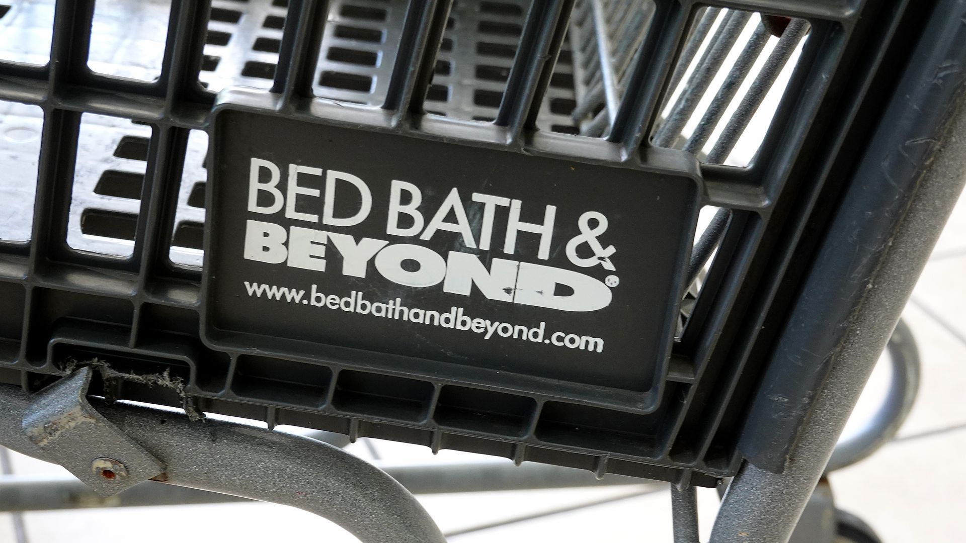 Retailer Bed Bath & Beyond's logo appears on the bottom of a metal shopping cart.
