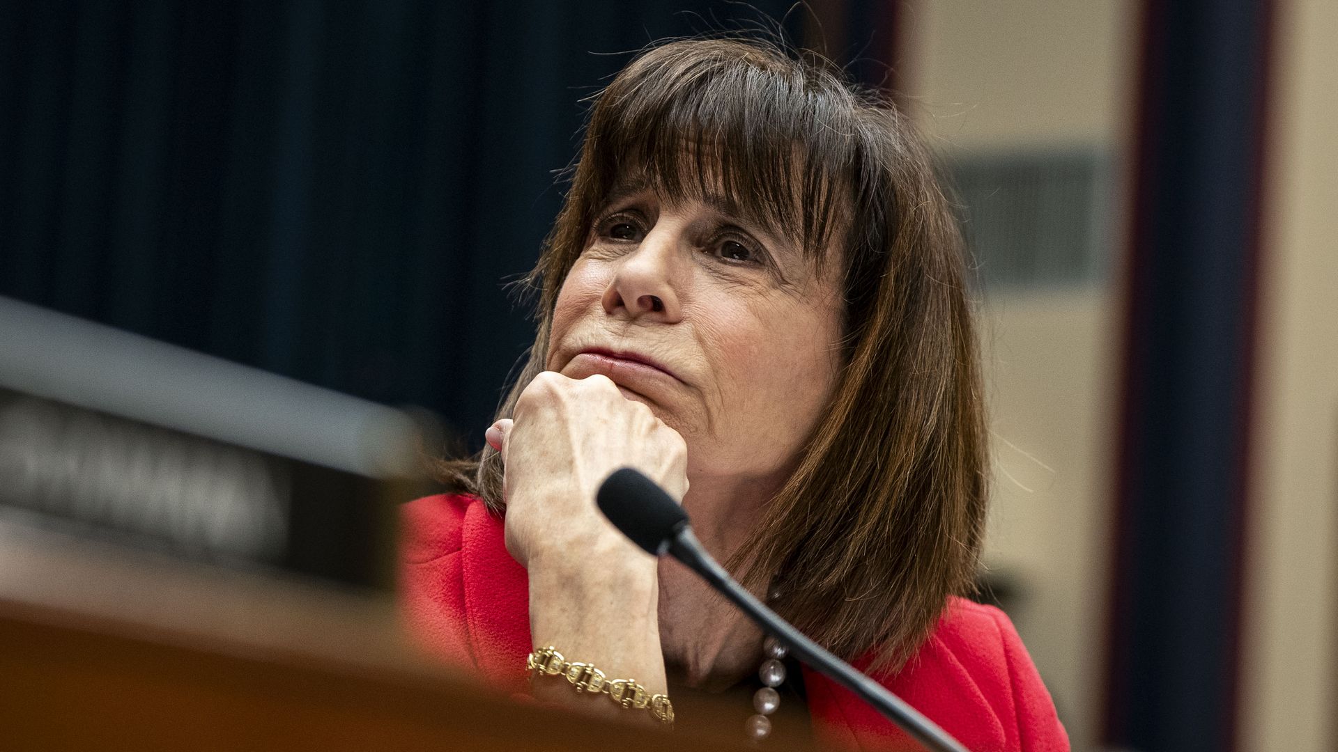 Rep. Kathy Manning, wearing a red blazer, sitting with her head on her hand at a committee hearing.