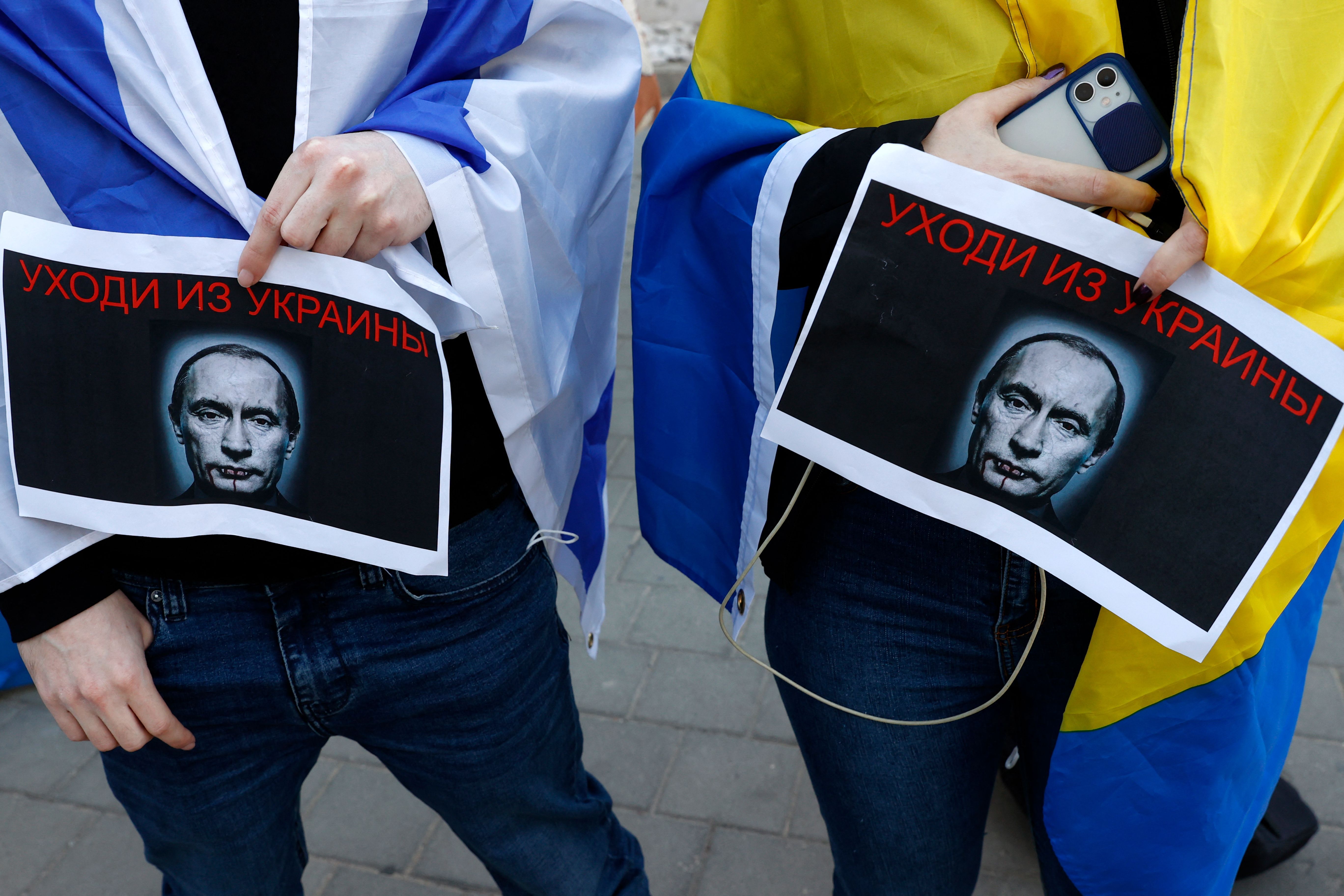 People clad in the Israeli (L) and Ukrainian flags take part in a protest against Russia's military operation in Ukraine, at the Russian embassy in the Israeli coastal city of Tel Aviv.