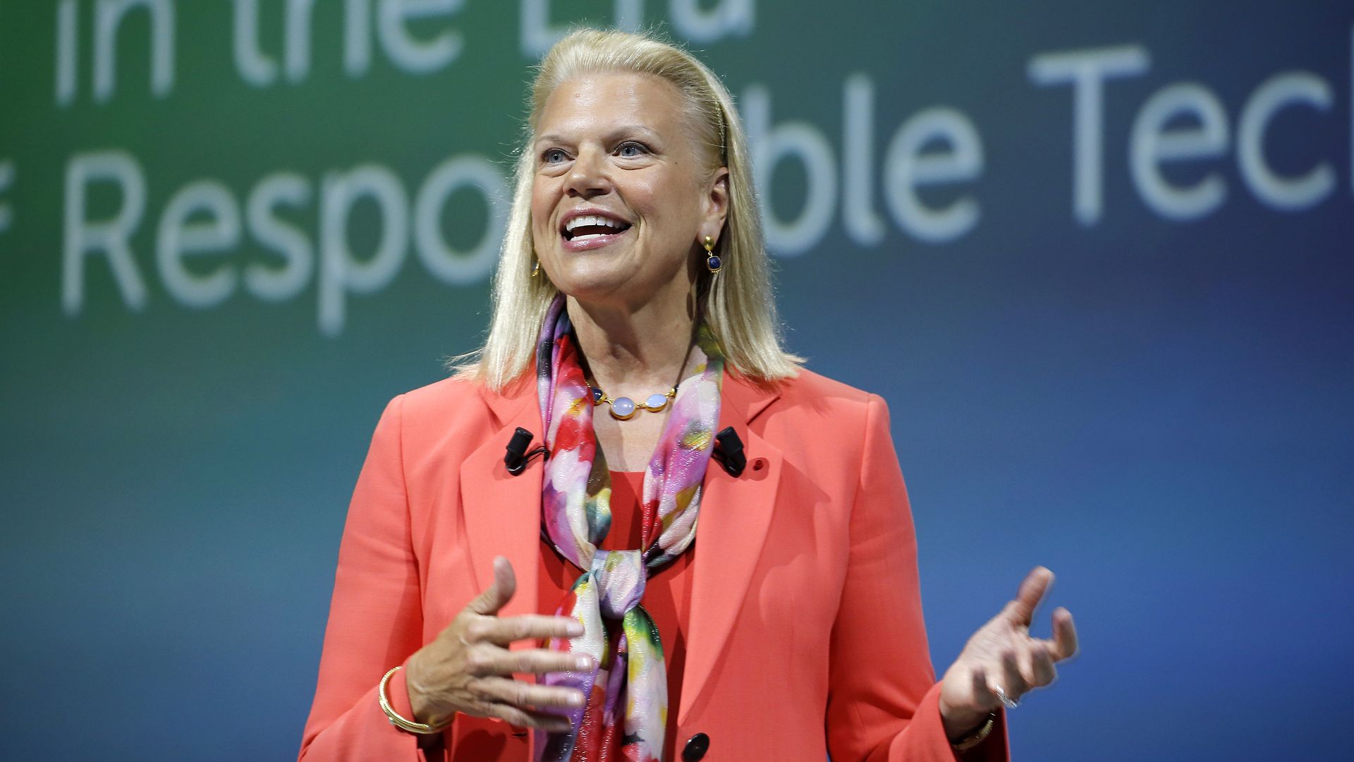 Ginni Rometty is a red jacket presents on stage