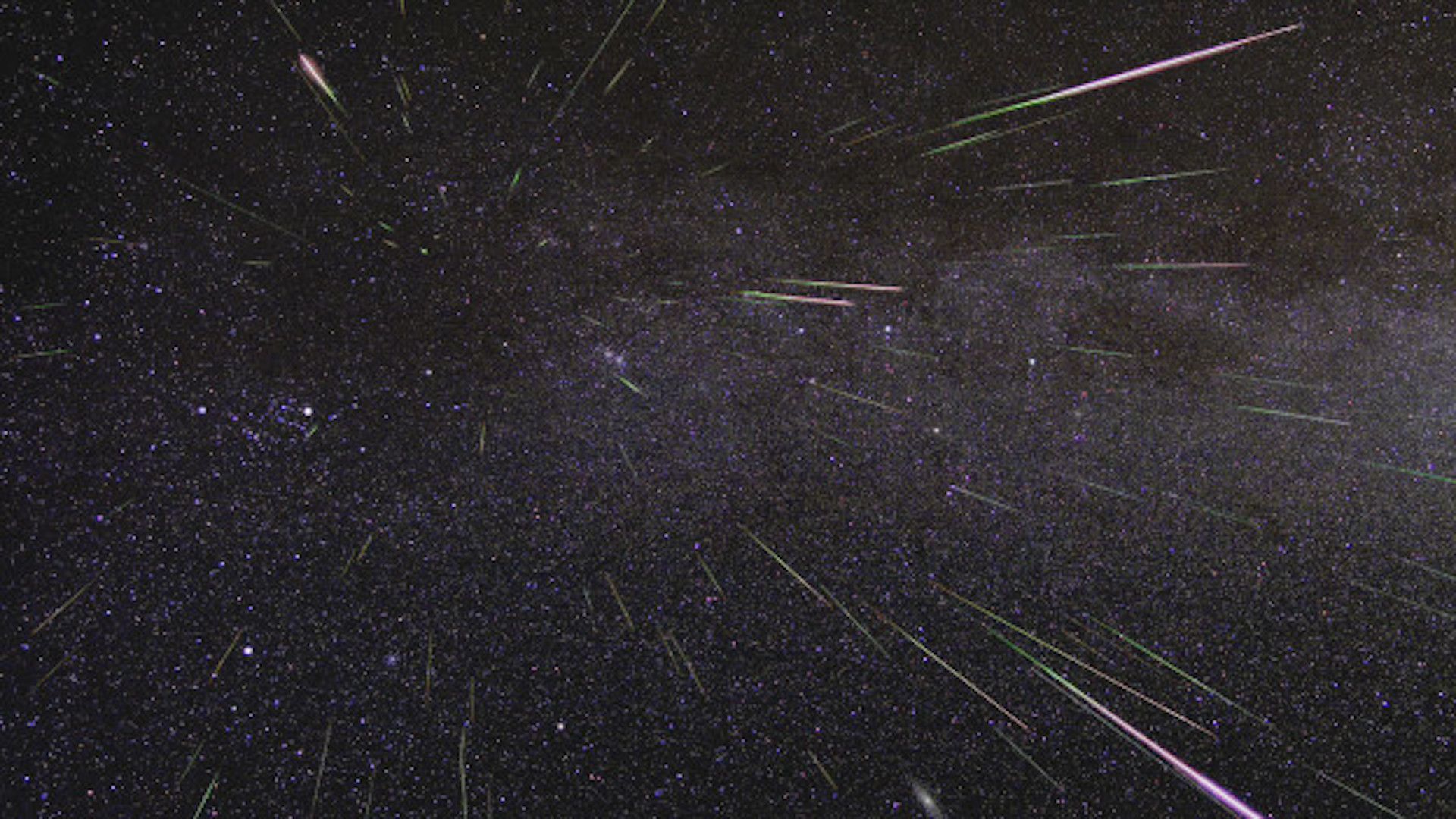 Streaks of meteors streaming in a dark, star-dotted sky.