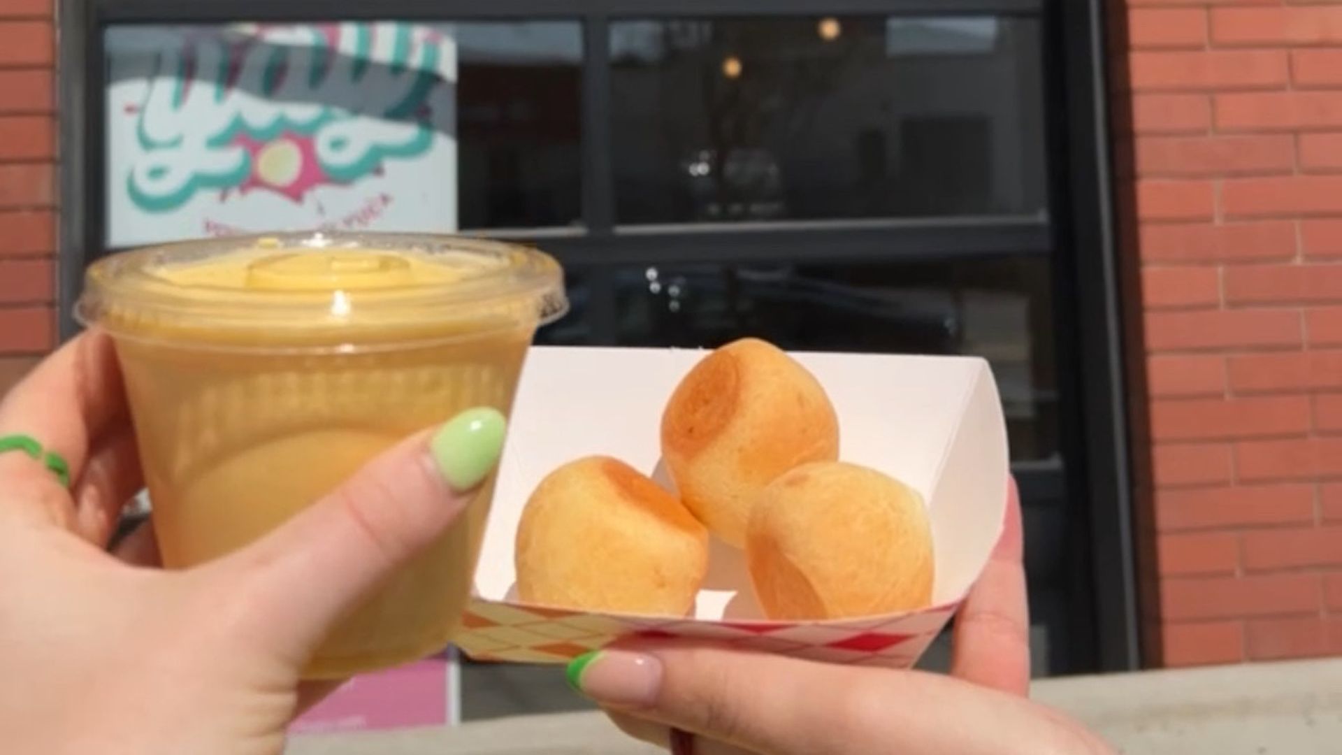 two hands holding a smoothie and doughnut holes