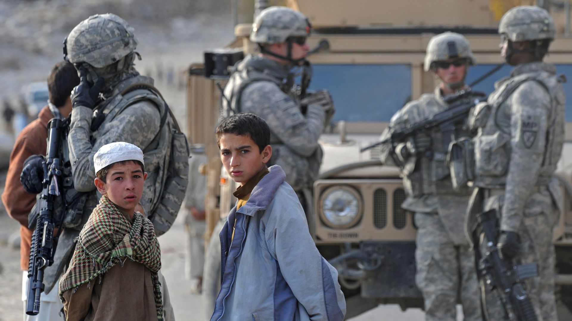 Soldiers standing next to children.