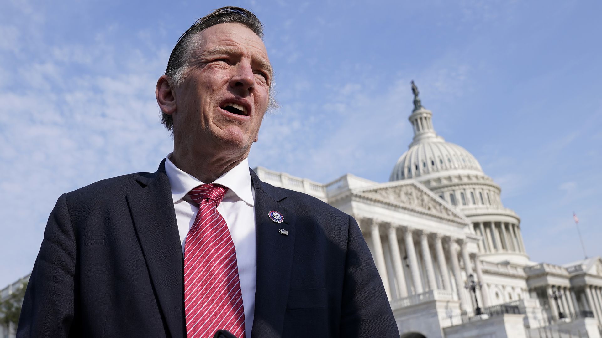 A man in a suit and tie standing in front of the U.S. Capitol.