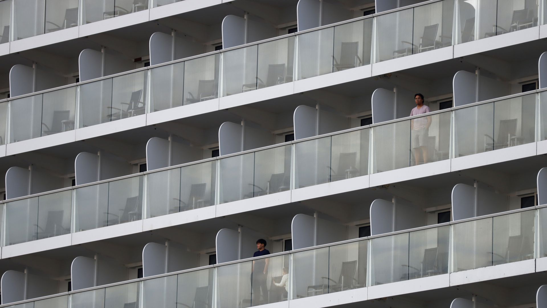 Passengers of a cruise ship are perched on their balconies.