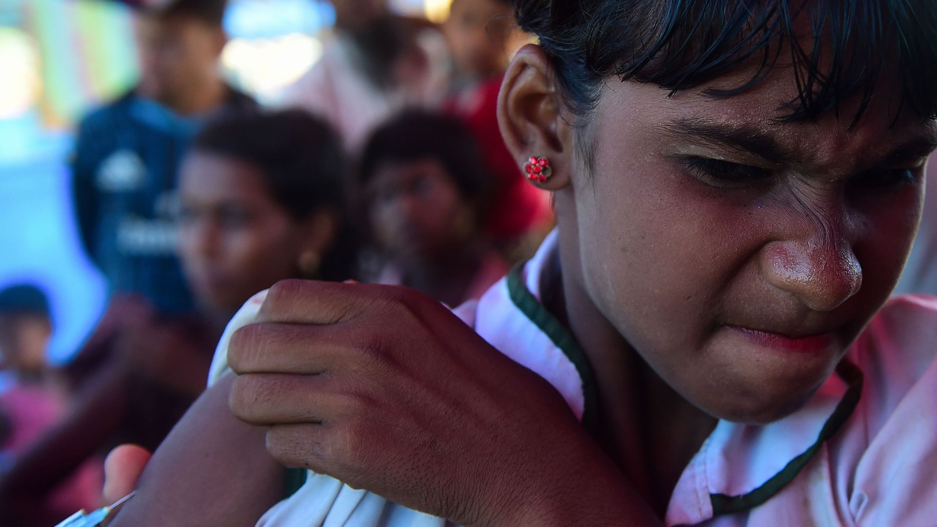 Photo of child in Bangladesh wincing as she receives her MMR shot