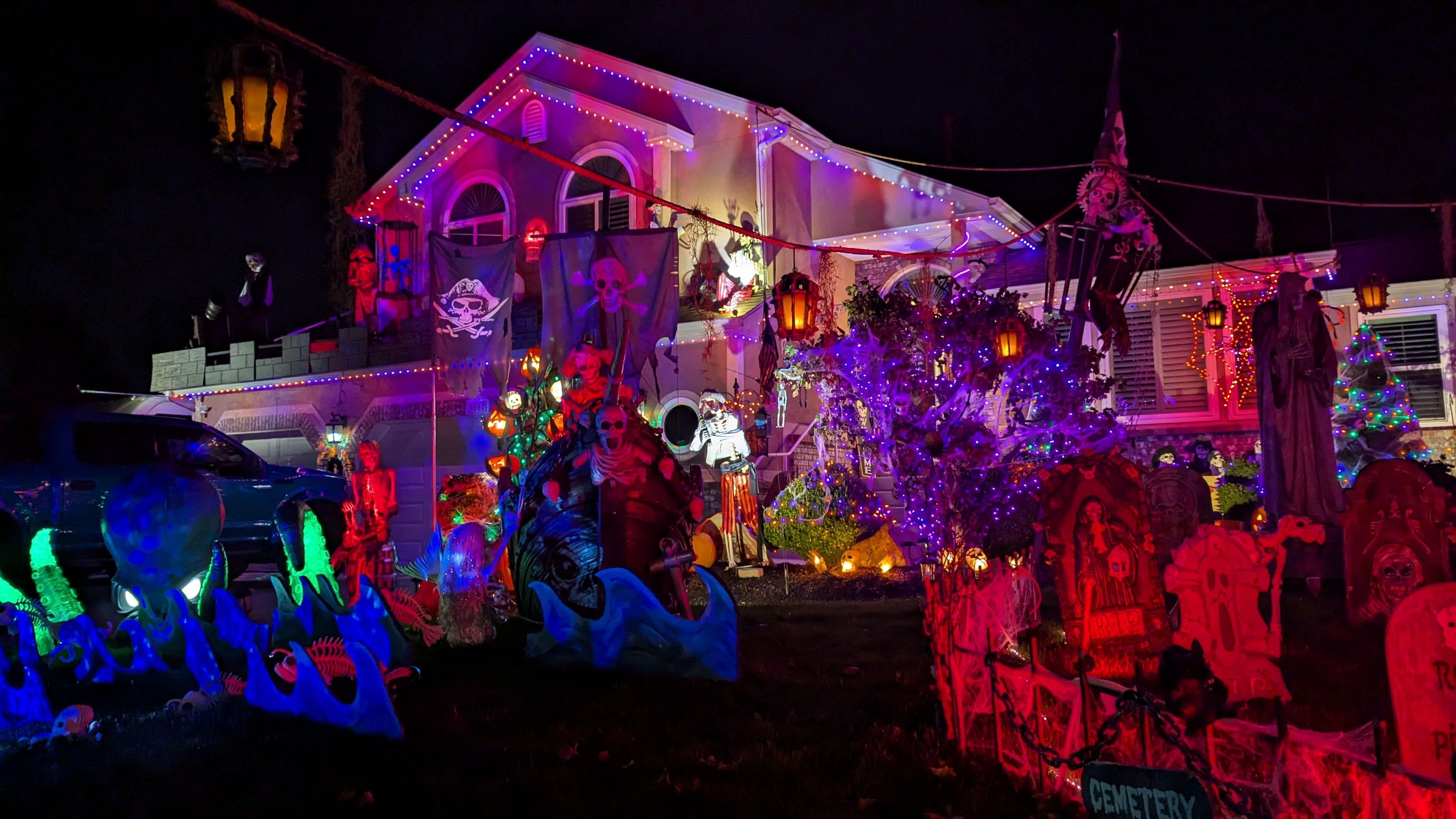 A pirate ship, sea monsters and a cemetery depicted in halloween decorations on a residential yard.