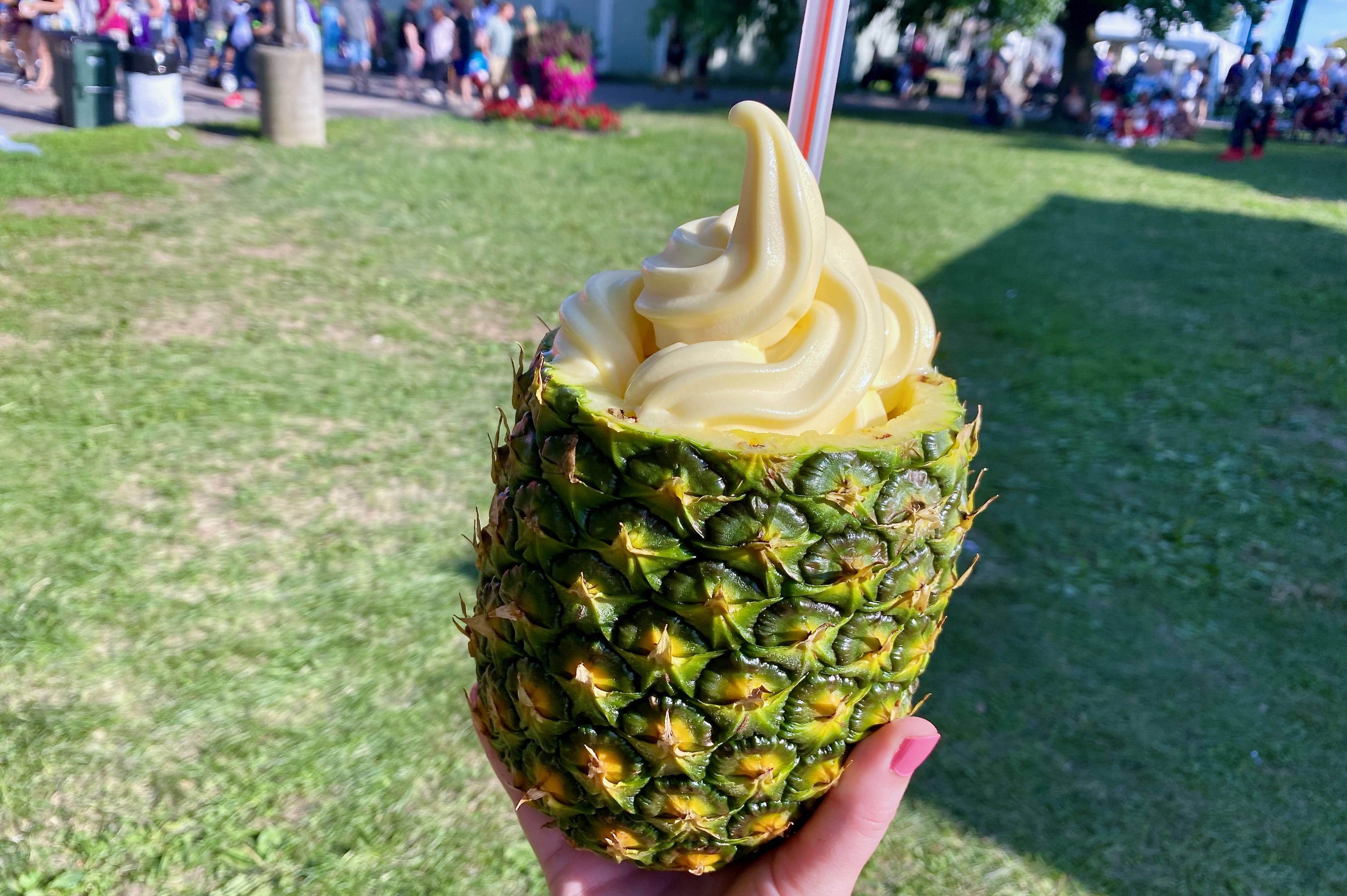 A hallowed whole pineapple with a straw and soft-serve ice cream on top