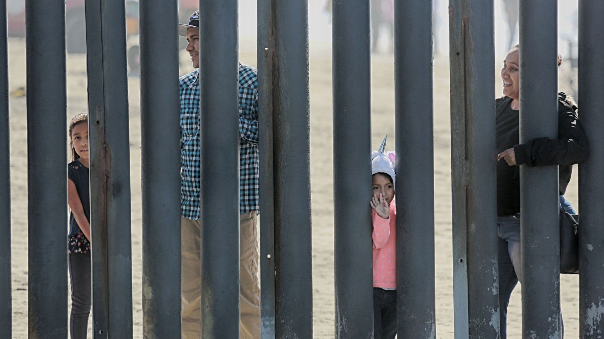 A family looks through metal bars in a fence