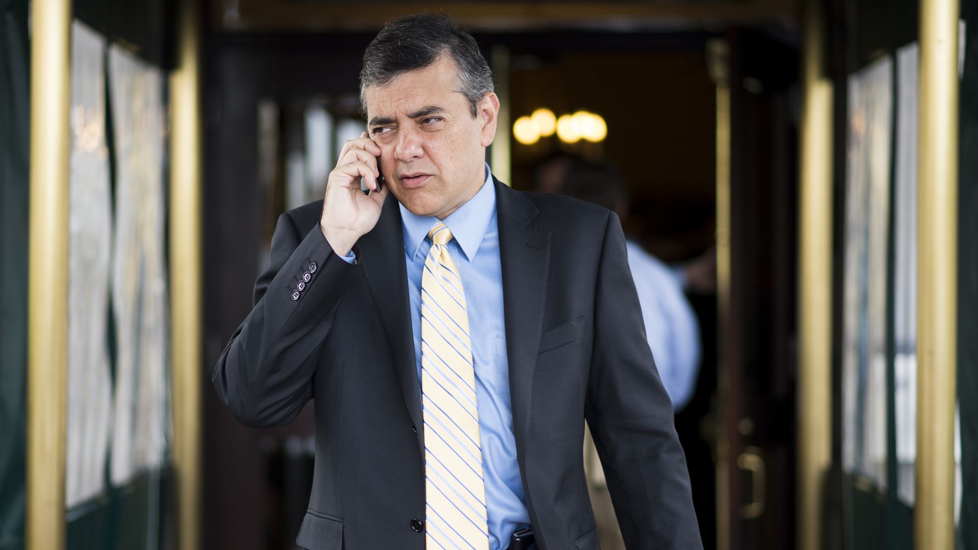 Photo of David Rivera holding a phone to his ear as he walks down a hallway