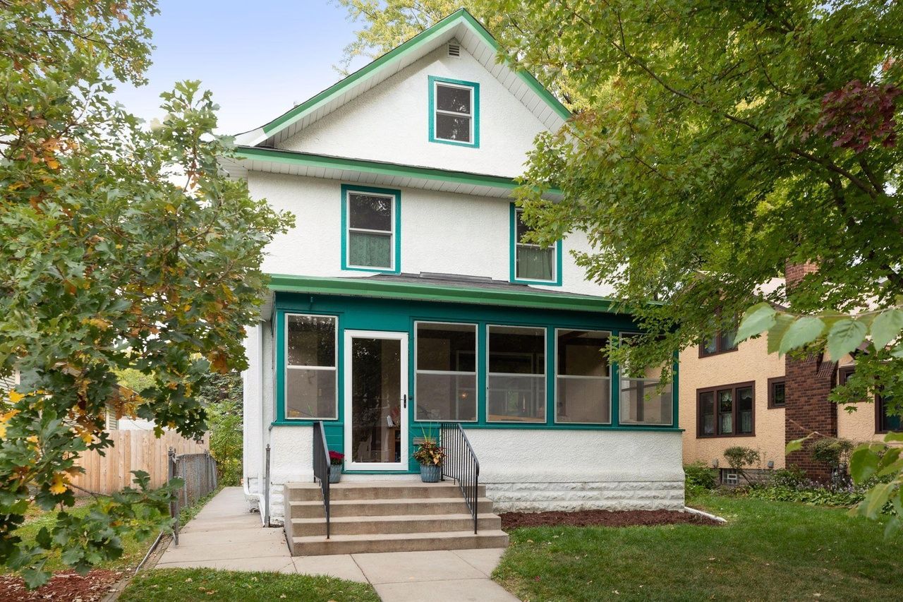 white home with enclosed front porch and green trim