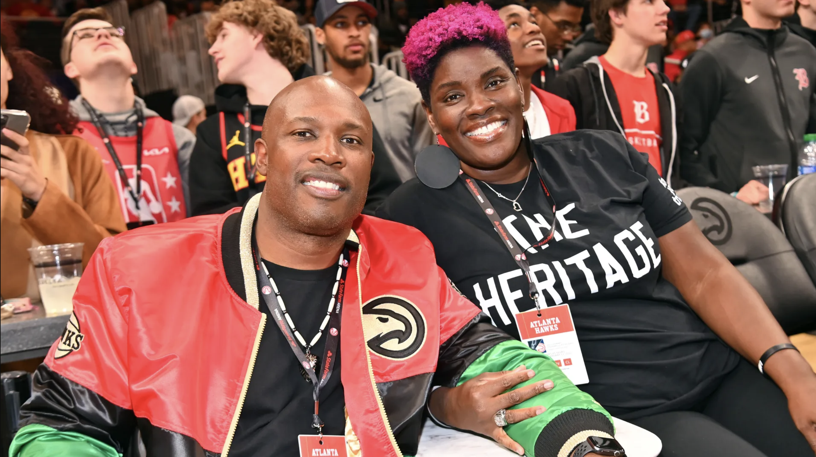 A photo of C.J. and Kelli Stewart smiling while sitting down at a basketball game