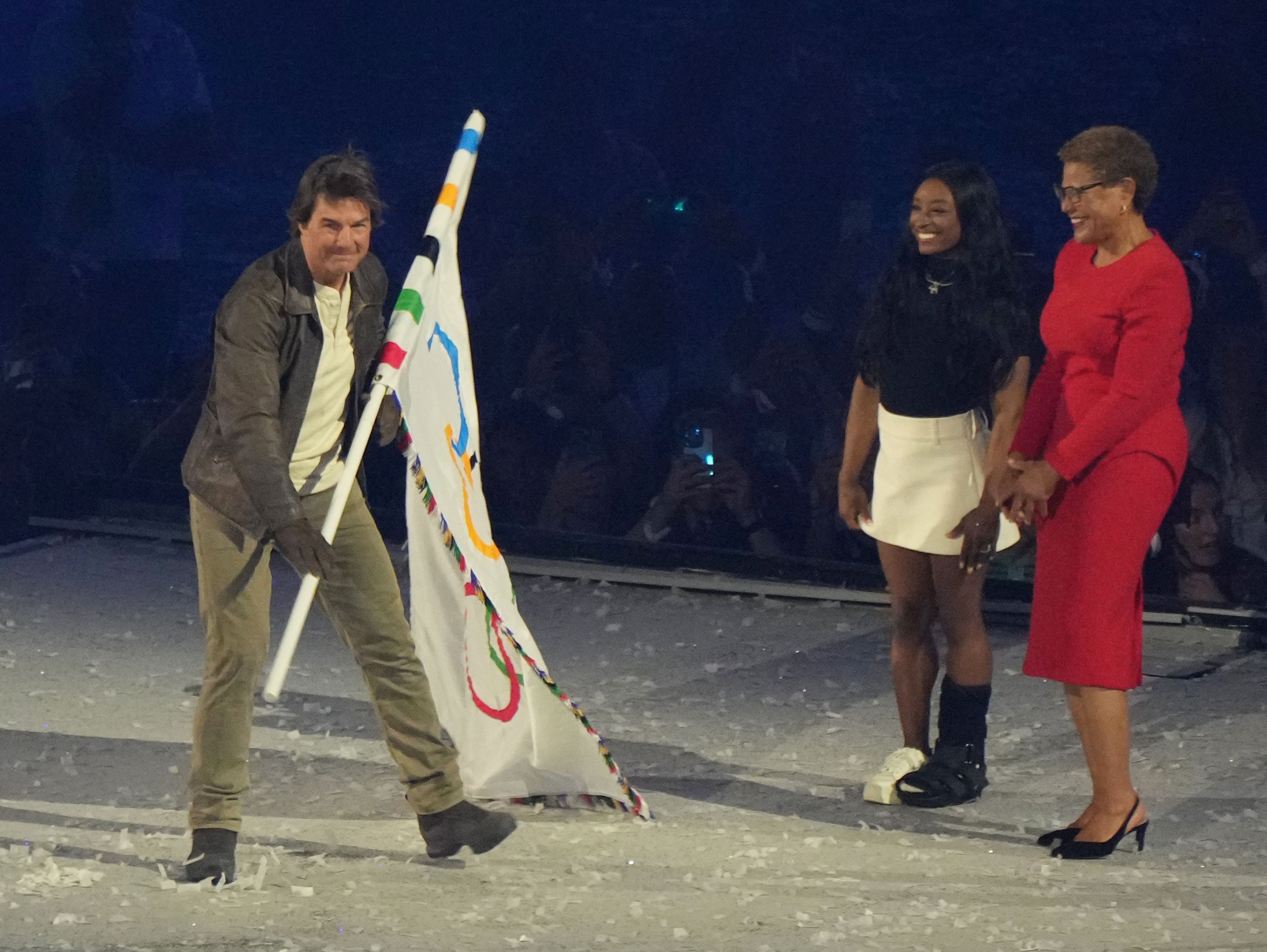 U.S.actor Tom Cruise (L) recieves the Olympic flag as Karen Bass (R), Mayor of Los Angeles and Simone Biles