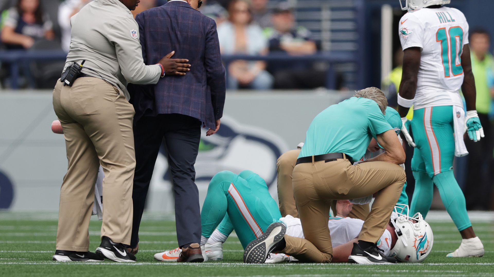 Football player laying on the floor with people standing around. 