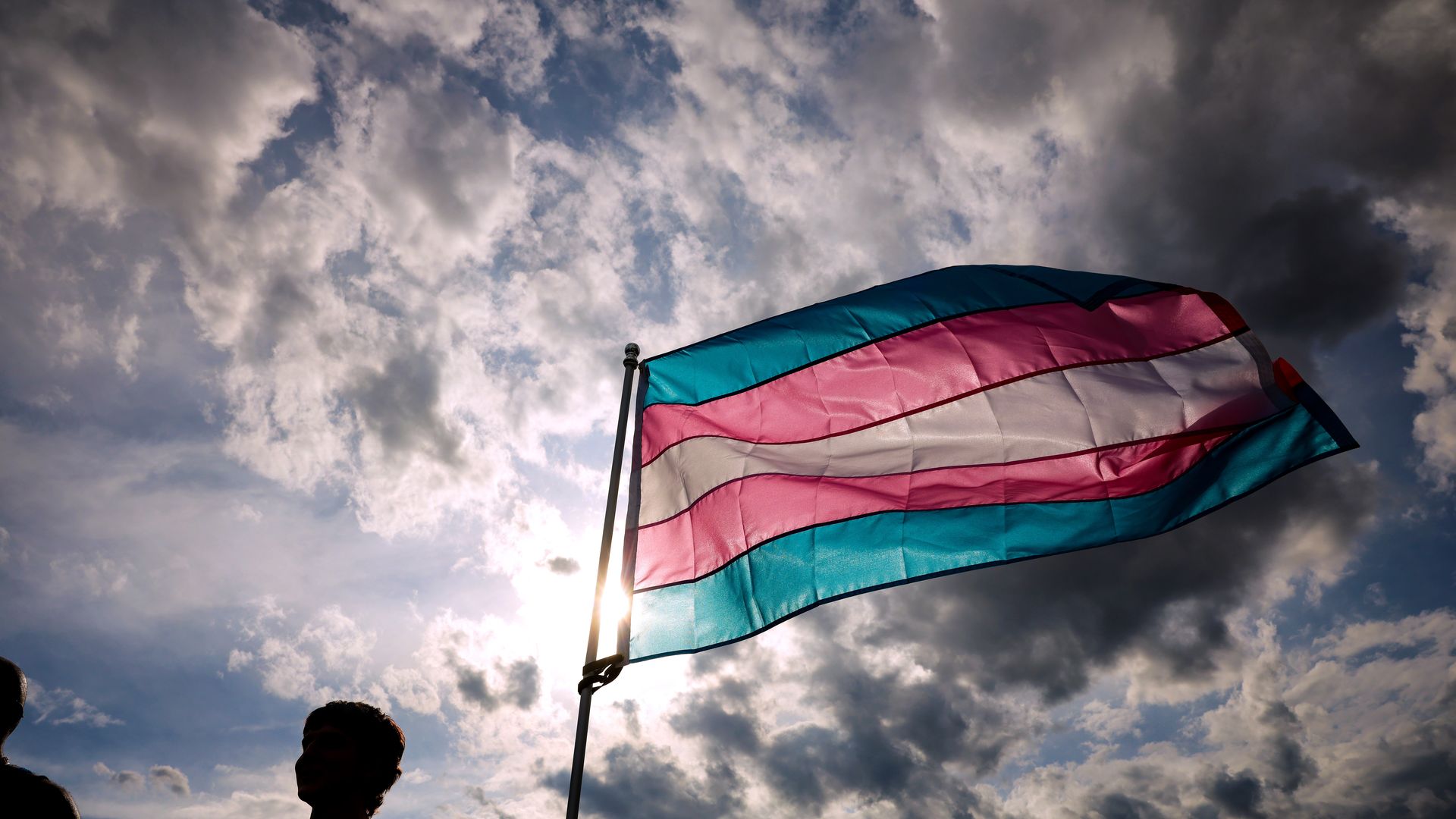 A transgender flag flies on a cloudy day. 