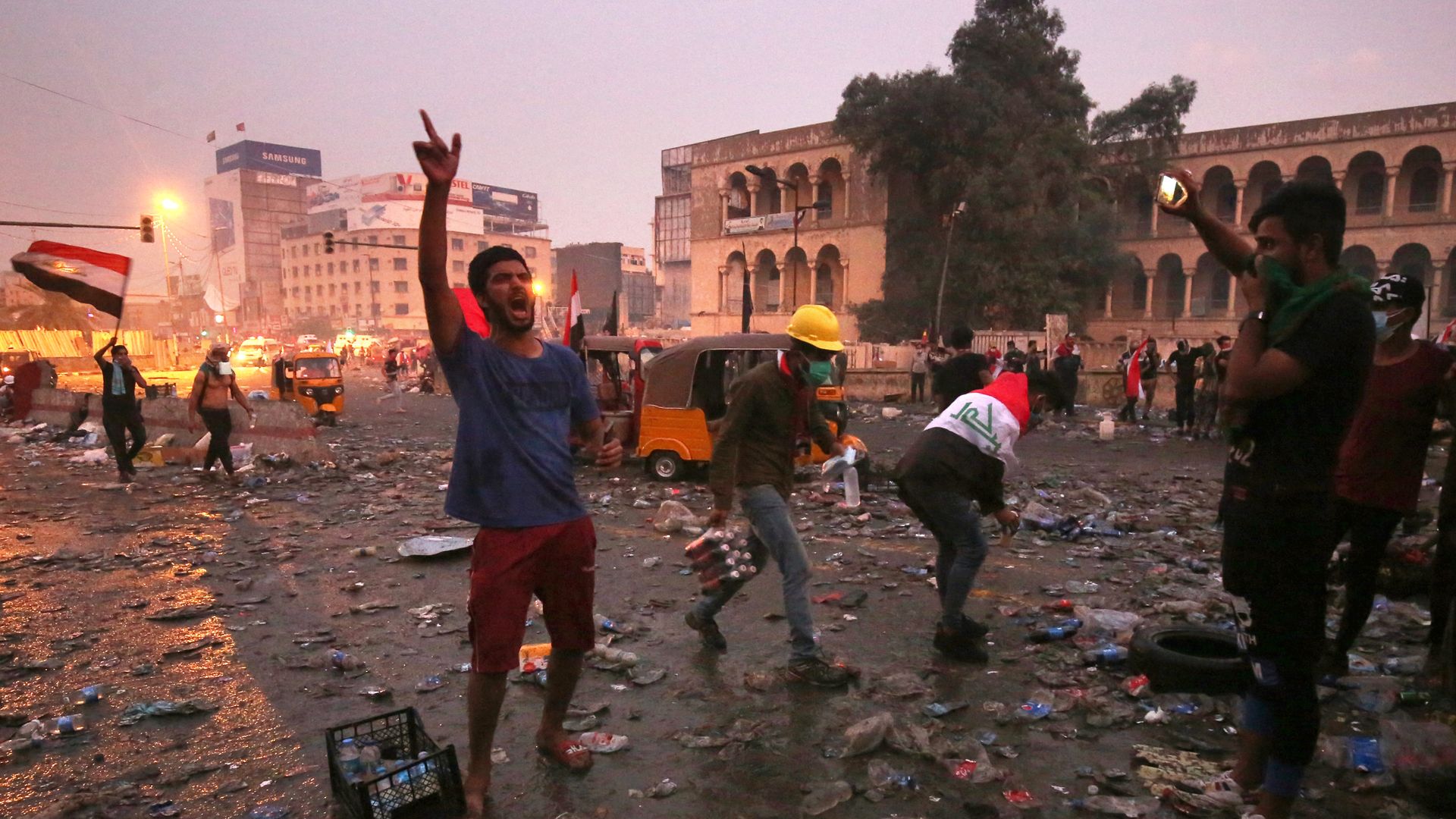 Iraqi anti-government protesters shout slogans after security forces fired tear gas.
