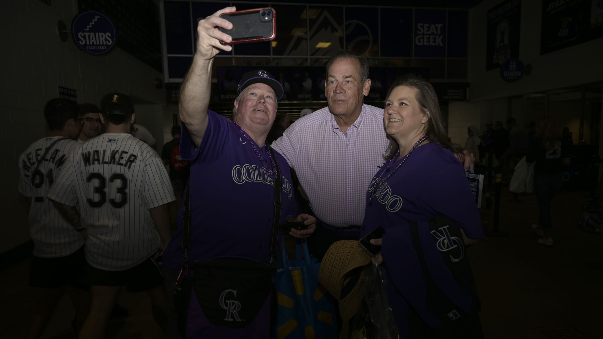 A man raises his hand to take a photograph while next to two other people. 