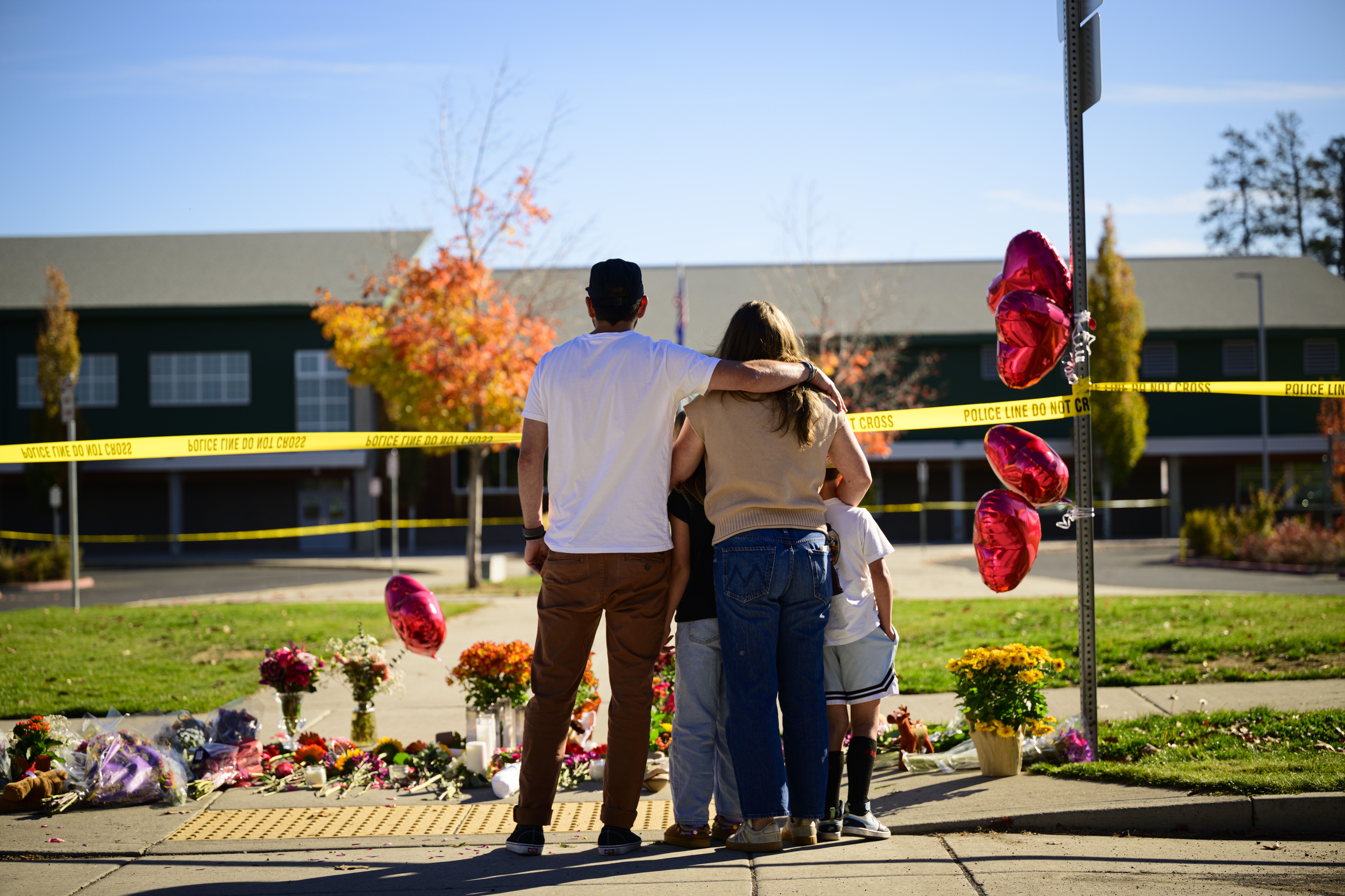 Community members grieve at the site of a makeshift memorial in front of Silver Rail Elementary School.